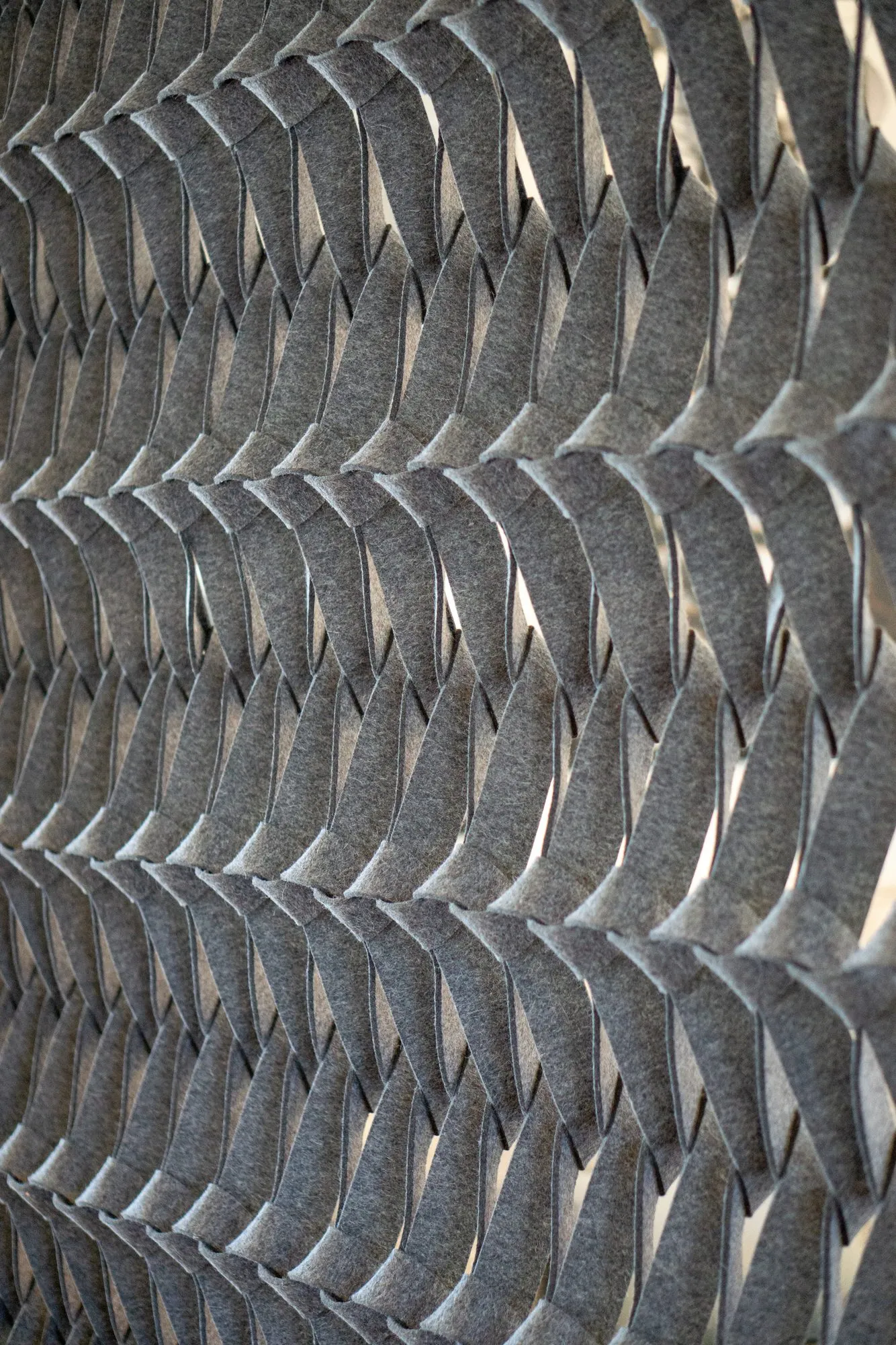 Multifamily interior detail: grey felt acoustic panel's interlocking curved strips