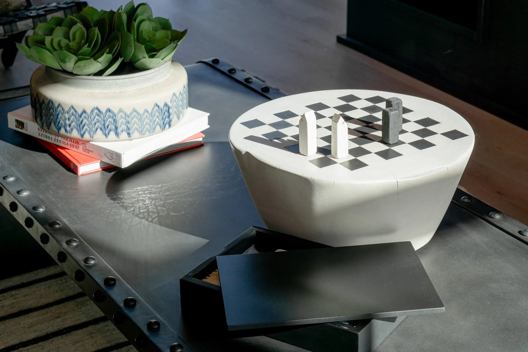 Multifamily interior detail: checkerboard drum table and a succulent in a blue and white pot on a riveted metal coffee table