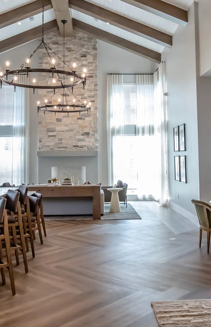 Multifamily clubroom with a stacked stone chimney under vaulted beams, interior design by Banko Design at Crofthouse West Cobb, Powder Springs, Georgia
