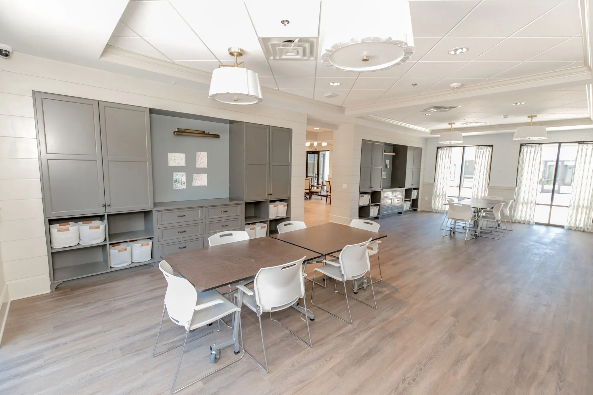 Senior living activity room with grey built-in cabinets and wood tables, interior design by Banko Design at The Phoenix at Braselton, Hoschton, Georgia