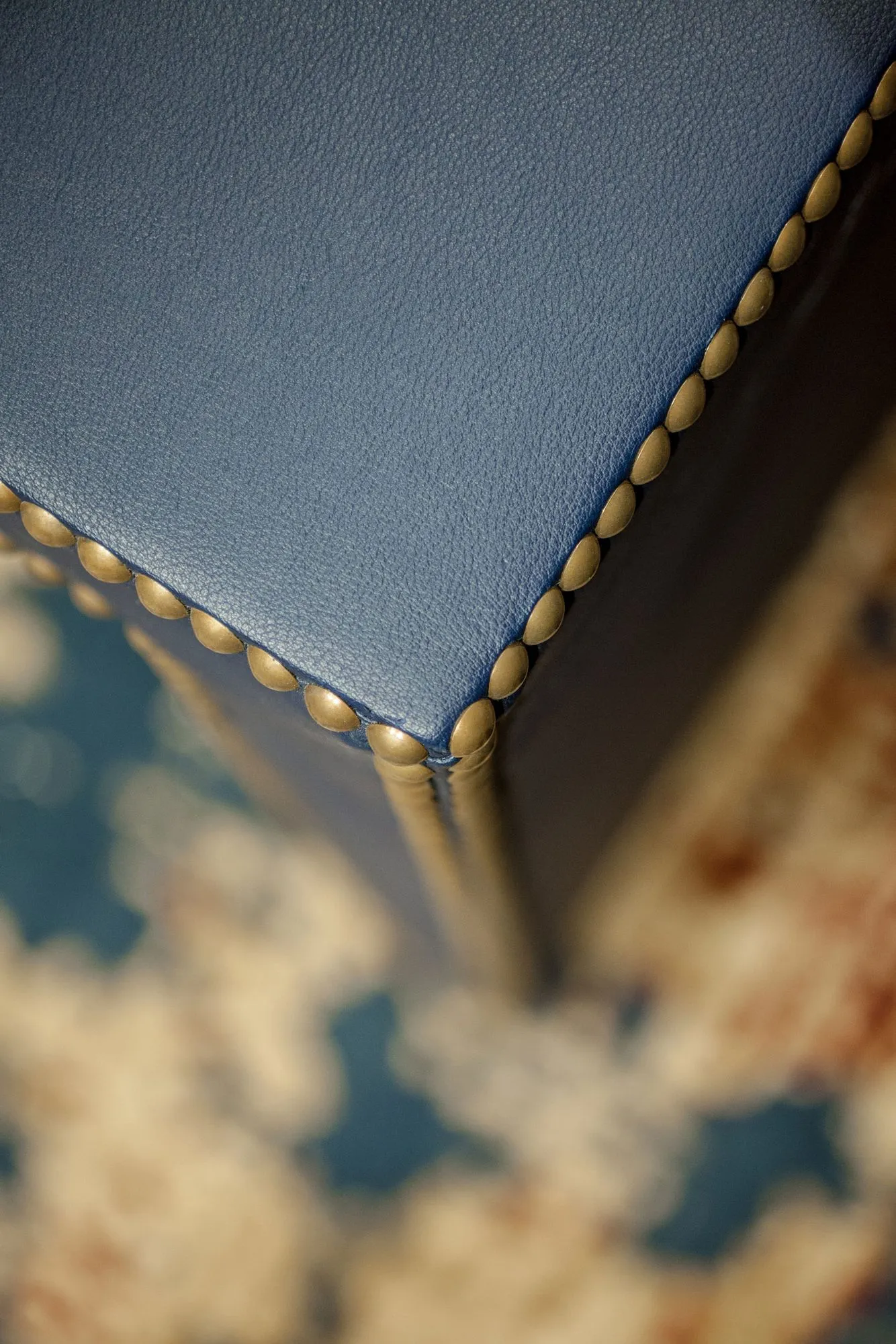 Senior living interior detail: nailhead trim along a blue leather upholstered edge above a patterned fabric
