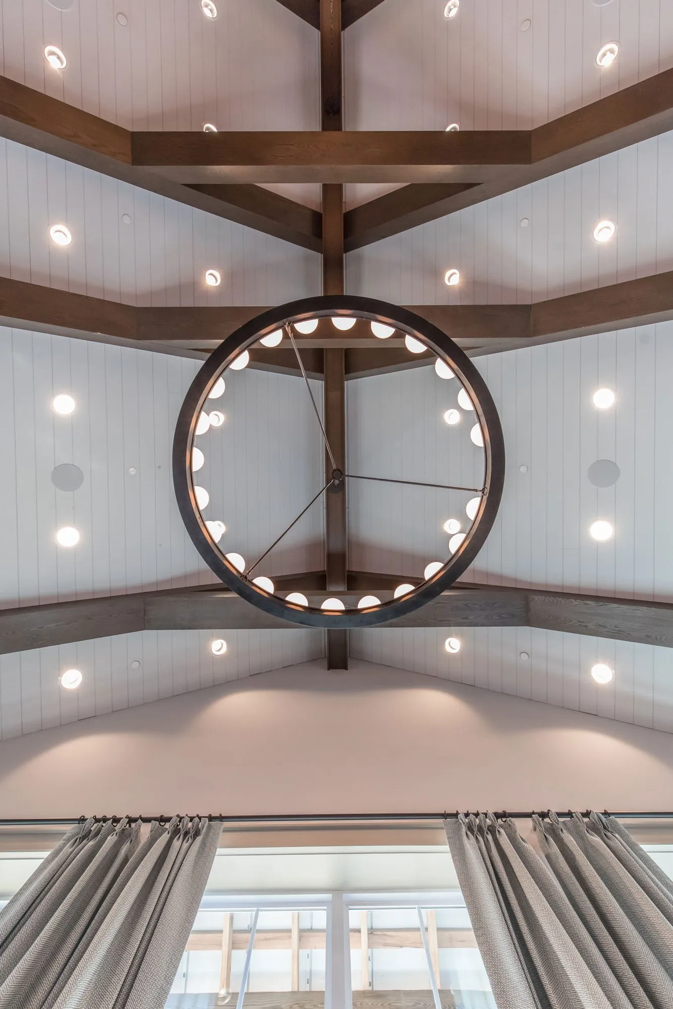 Senior living interior detail: looking up at a ring chandelier hanging from stained beams in a white vaulted ceiling