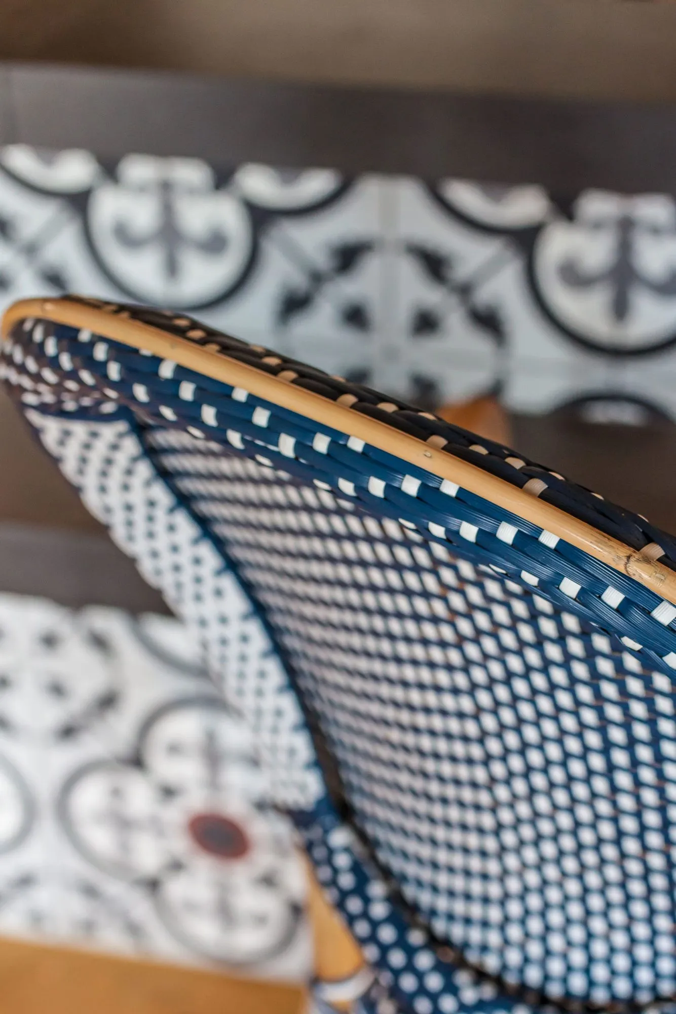 Senior living interior detail: blue and white woven rattan chair back against black and white patterned tile