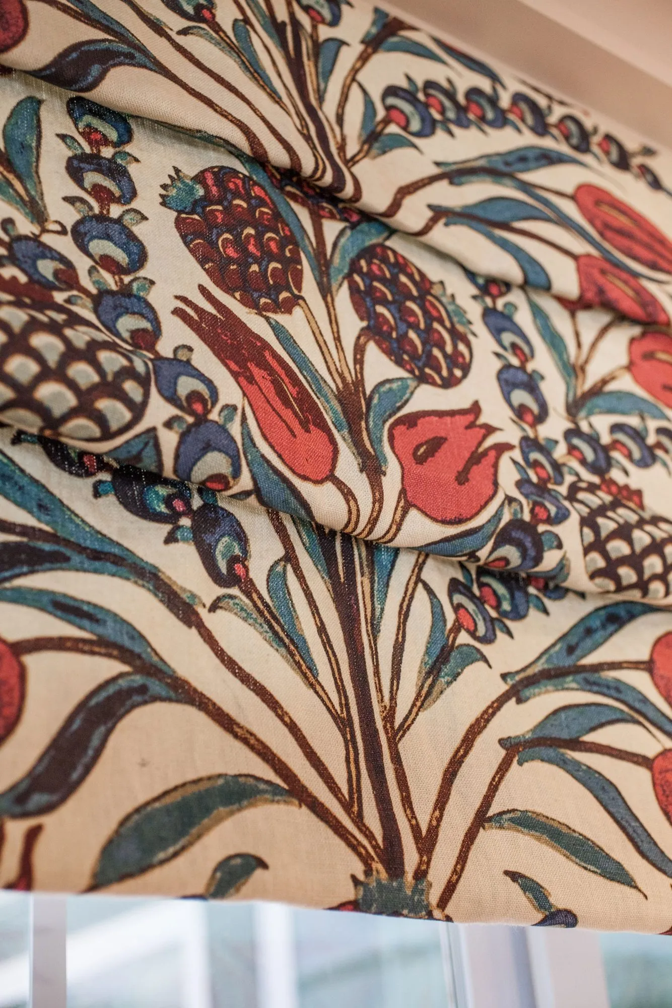Senior living interior detail: roman shade printed with red and blue pomegranate and tulip branches on cream