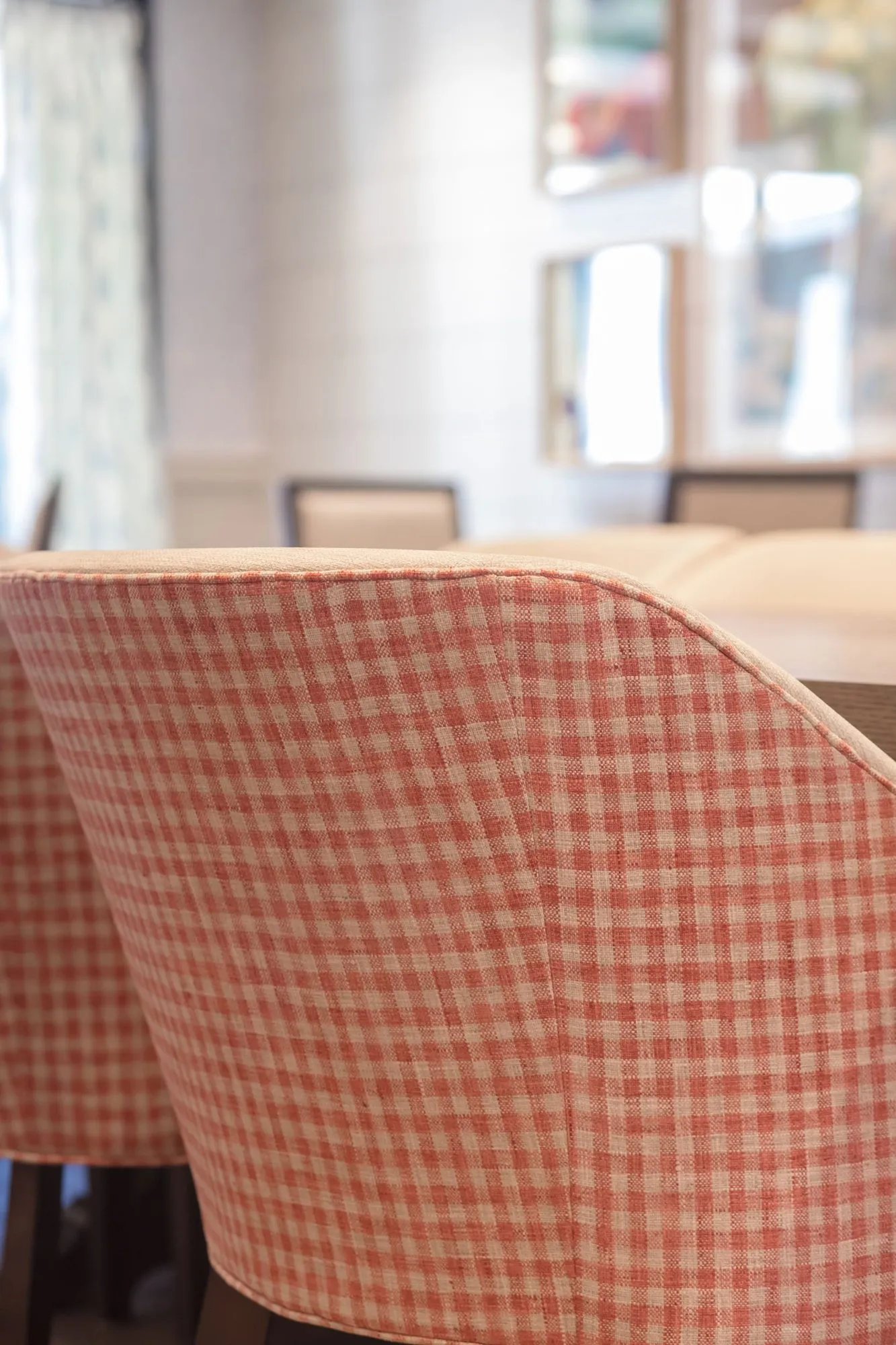 Senior living interior detail: back of a red and white gingham upholstered chair at a table