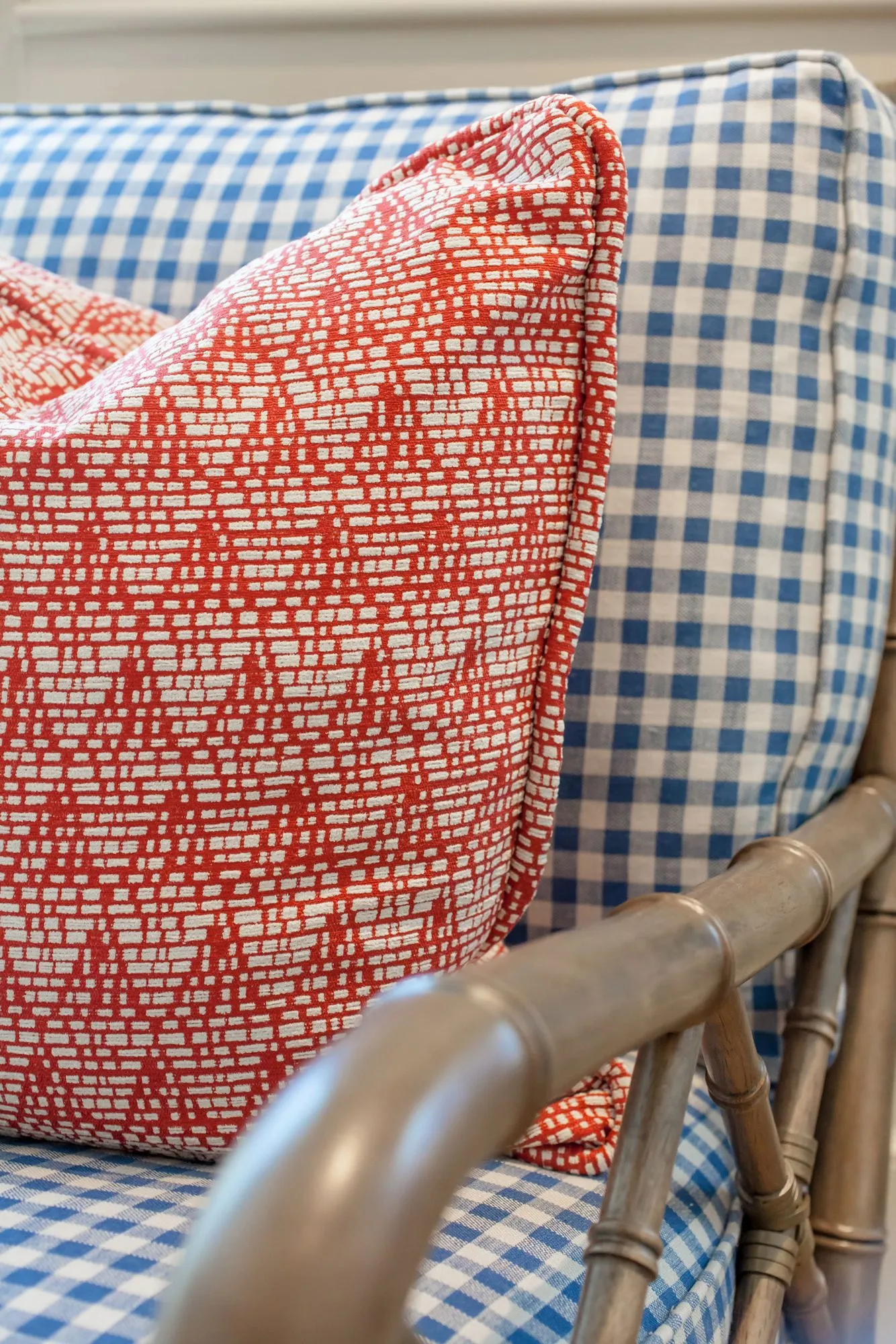 Senior living interior detail: red and white patterned pillow on a blue gingham chair with a faux bamboo frame