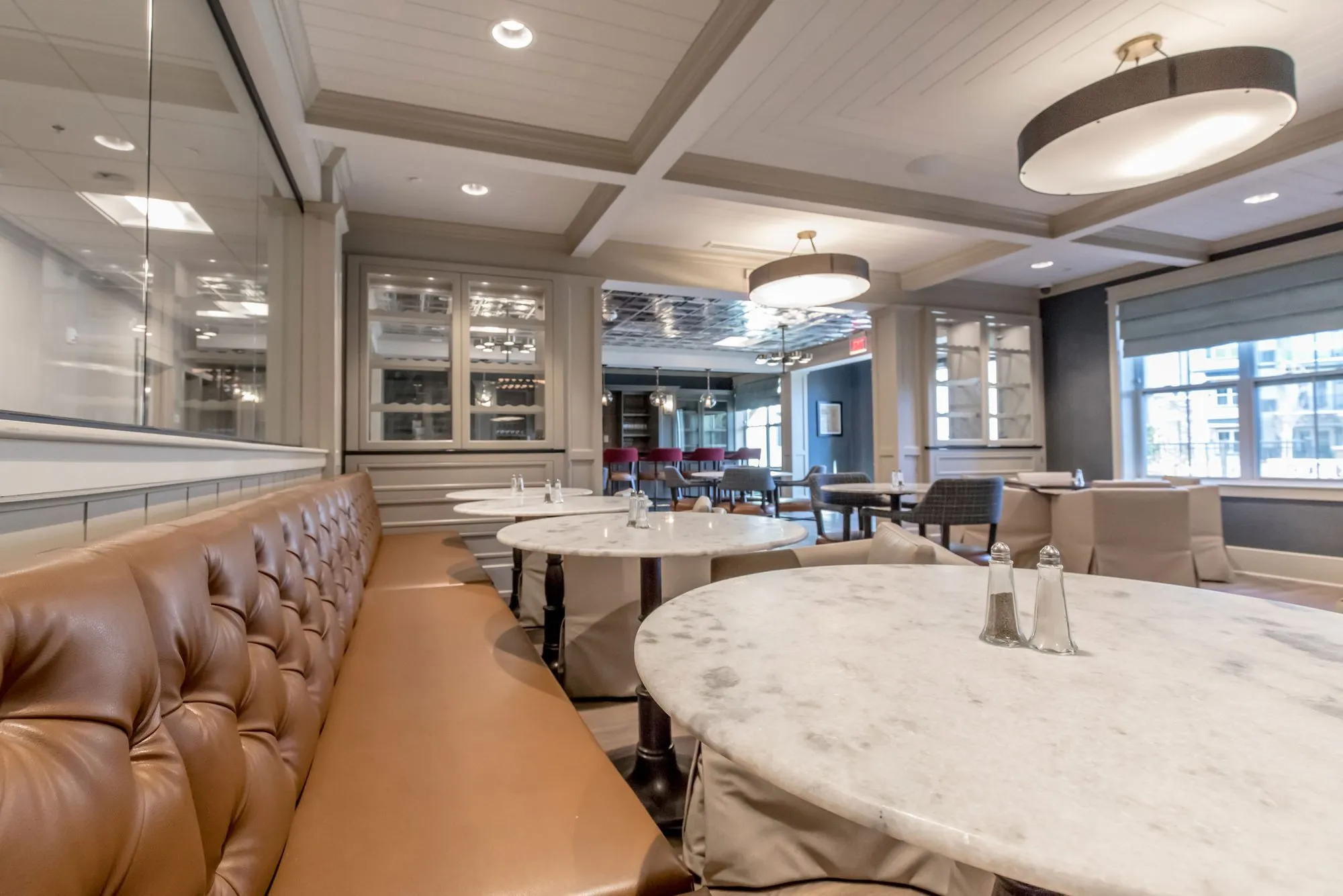 Senior living lounge, low angle along the cognac tufted banquette to salt and pepper shakers on a marble table