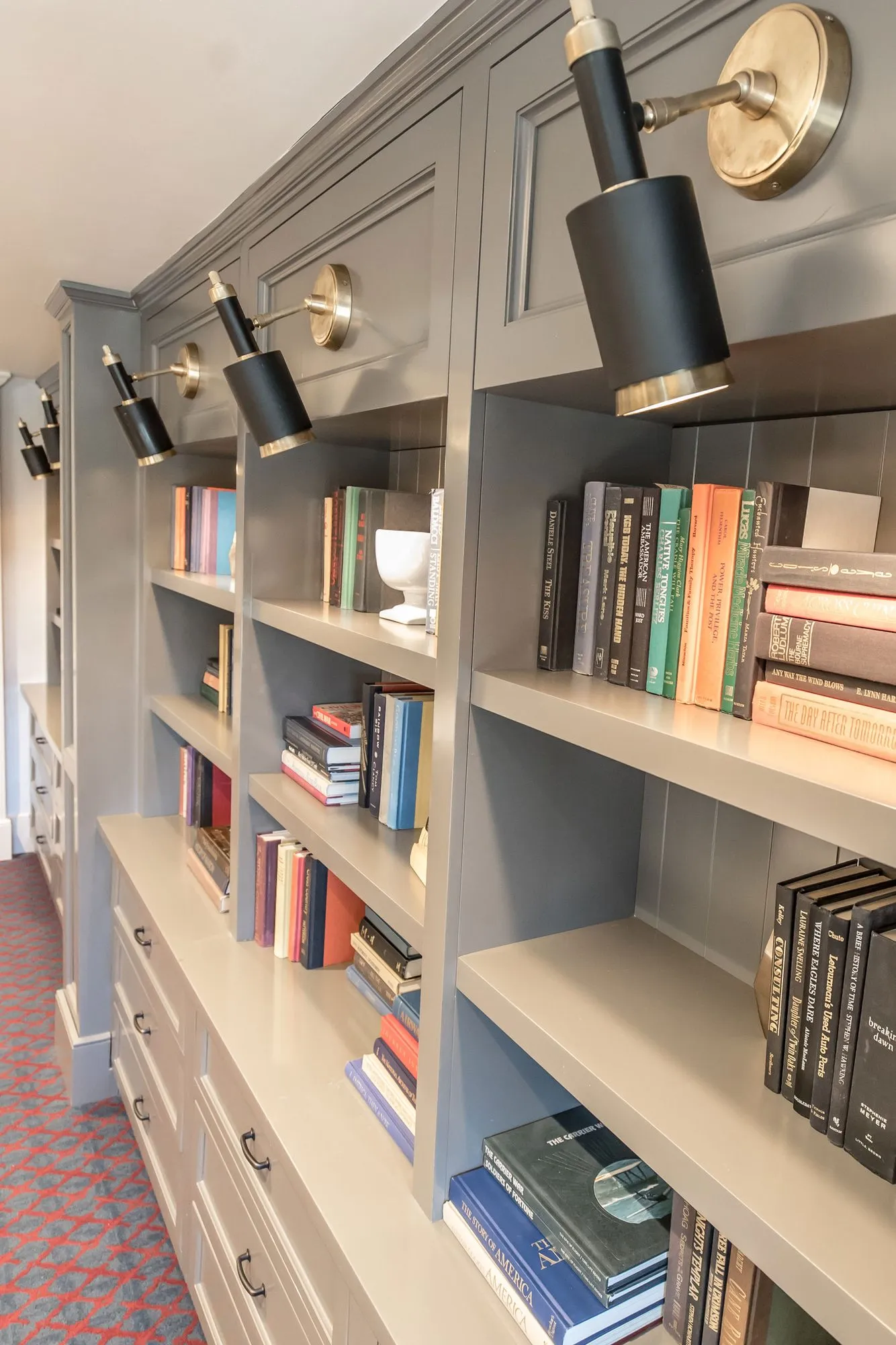 Senior living corridor with grey built-in bookcases and black and brass picture lights