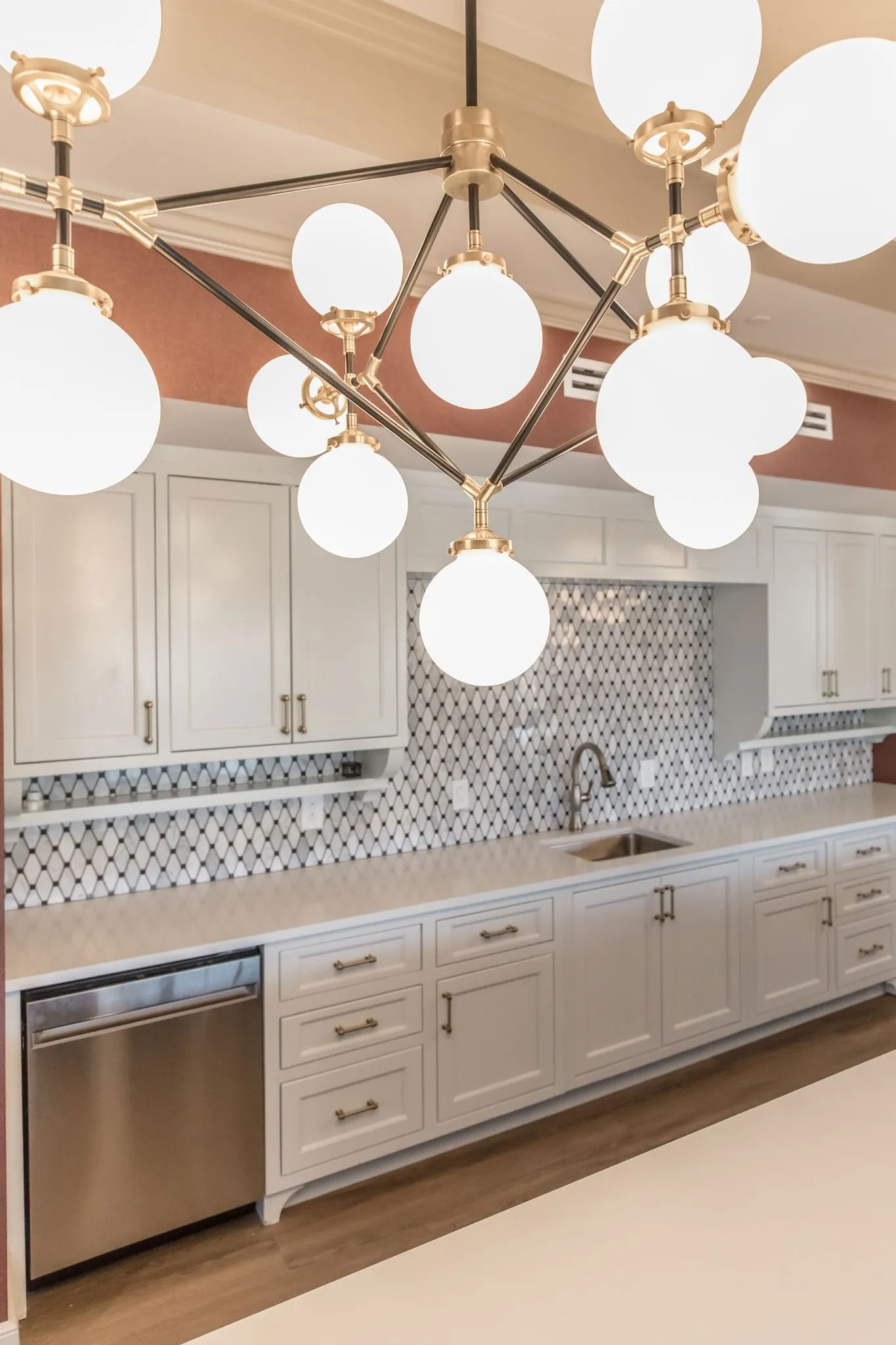 Senior living demonstration kitchen with a brass and opal globe chandelier above the patterned tile backsplash