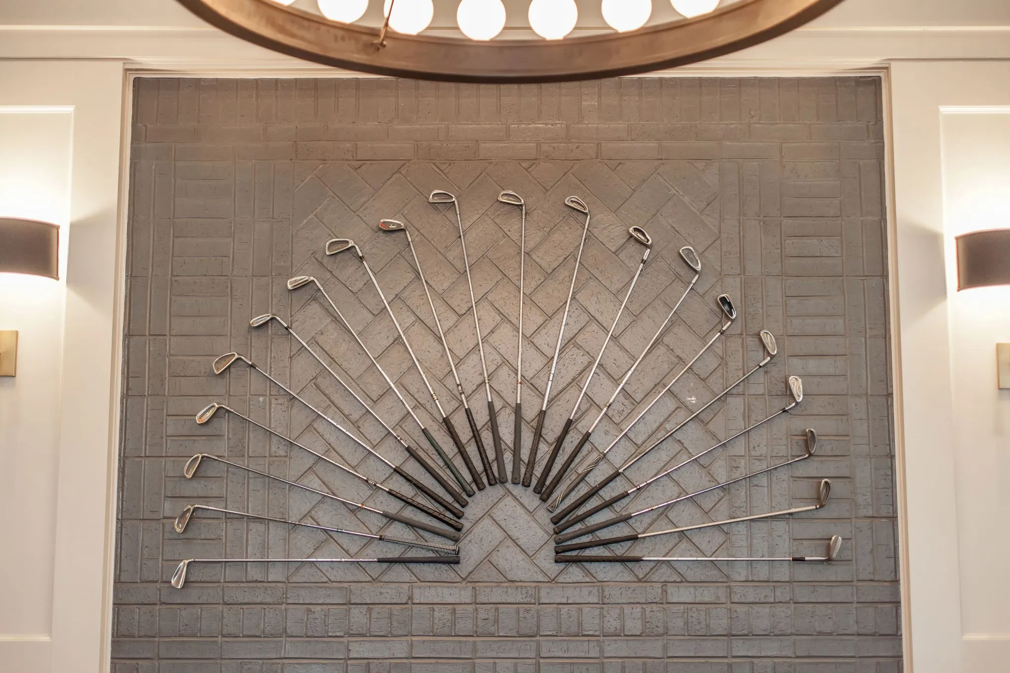 Senior living interior detail: fan of golf irons mounted as artwork on the herringbone tiled fireplace
