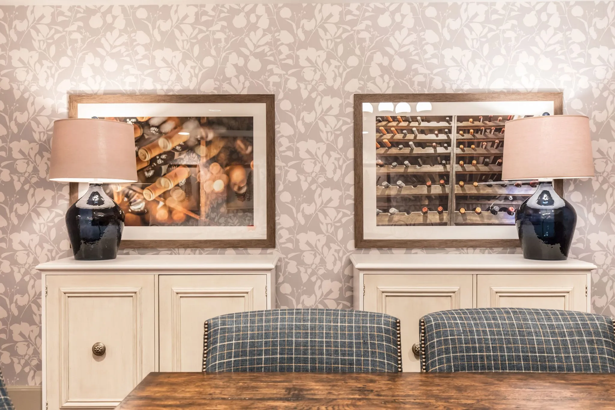 Senior living private dining room with plaid chairs at a rustic table below framed wine cellar photographs and navy lamps