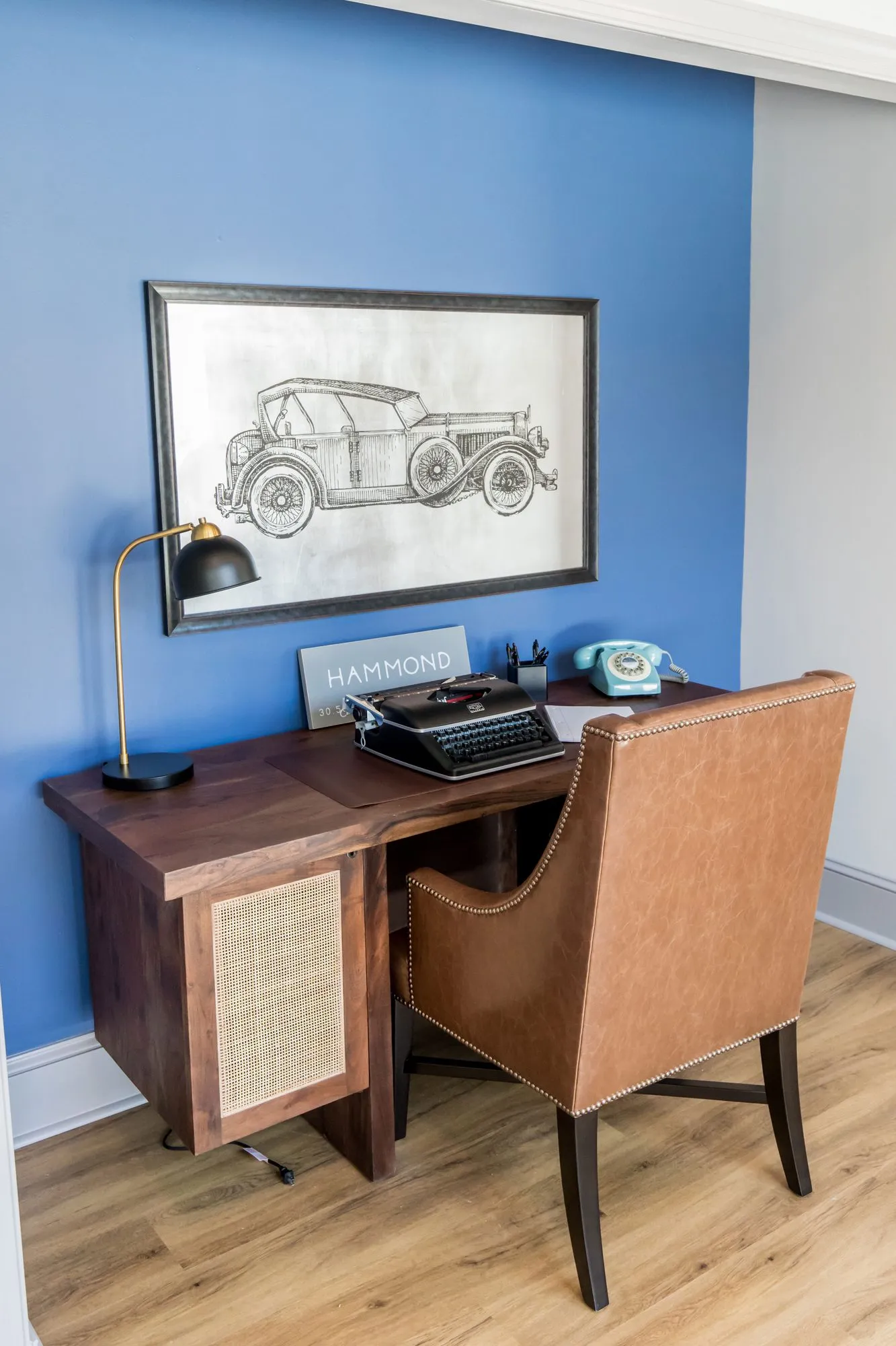 Senior living interior detail: writing desk with a typewriter and teal rotary phone against a royal blue wall