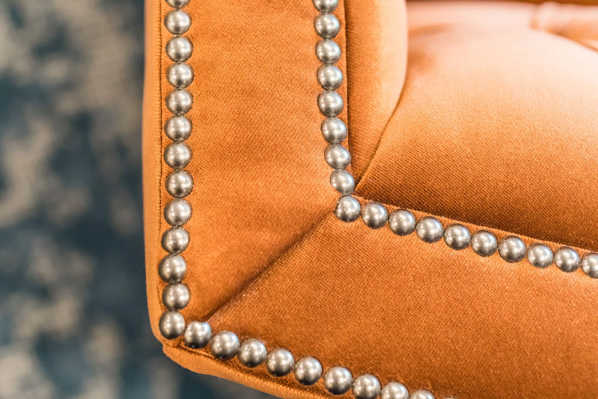 Senior living interior detail: nailhead trim along the corner of orange velvet upholstery