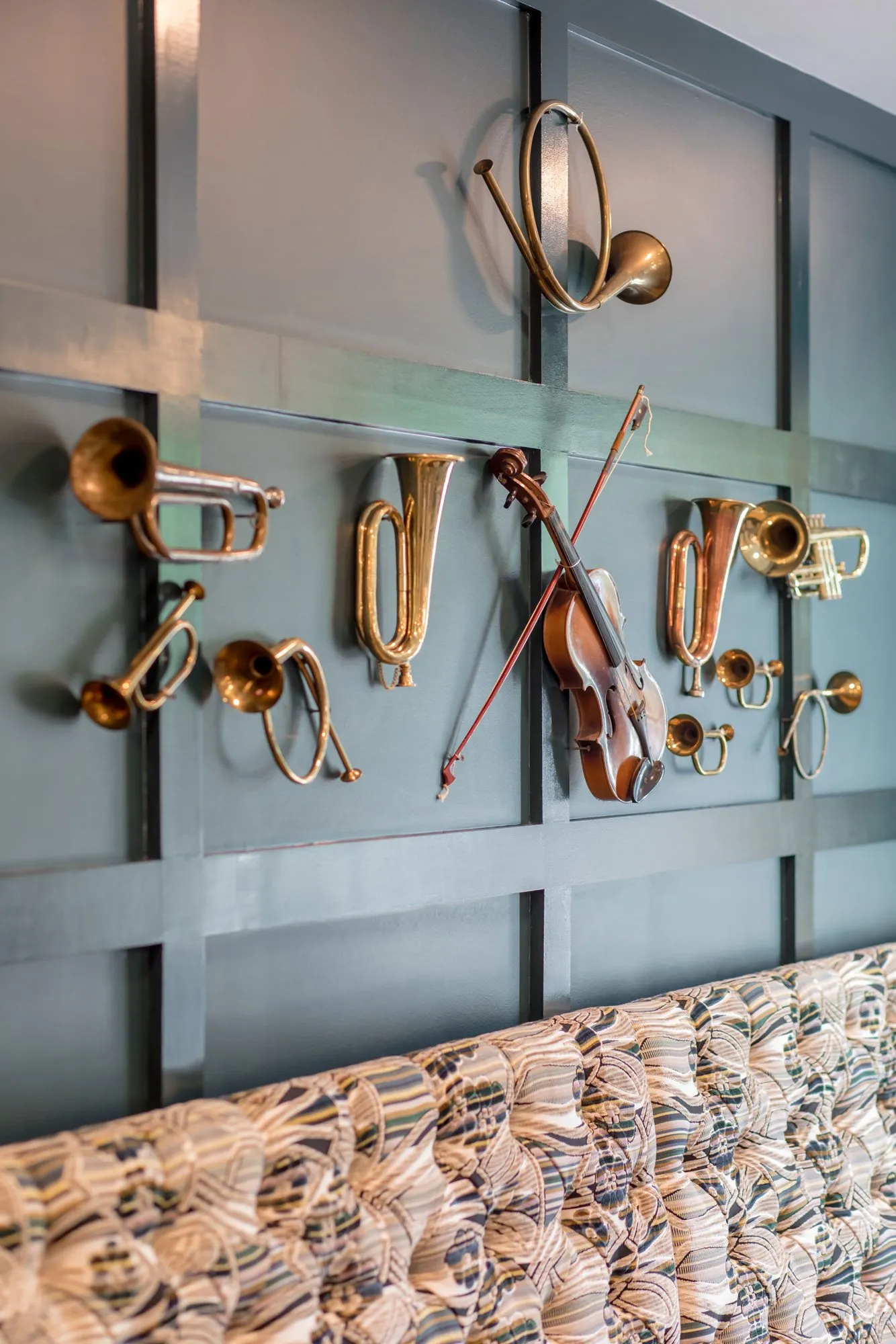 Senior living bistro with brass horns and a violin on dark teal panelling over the top of a patterned banquette