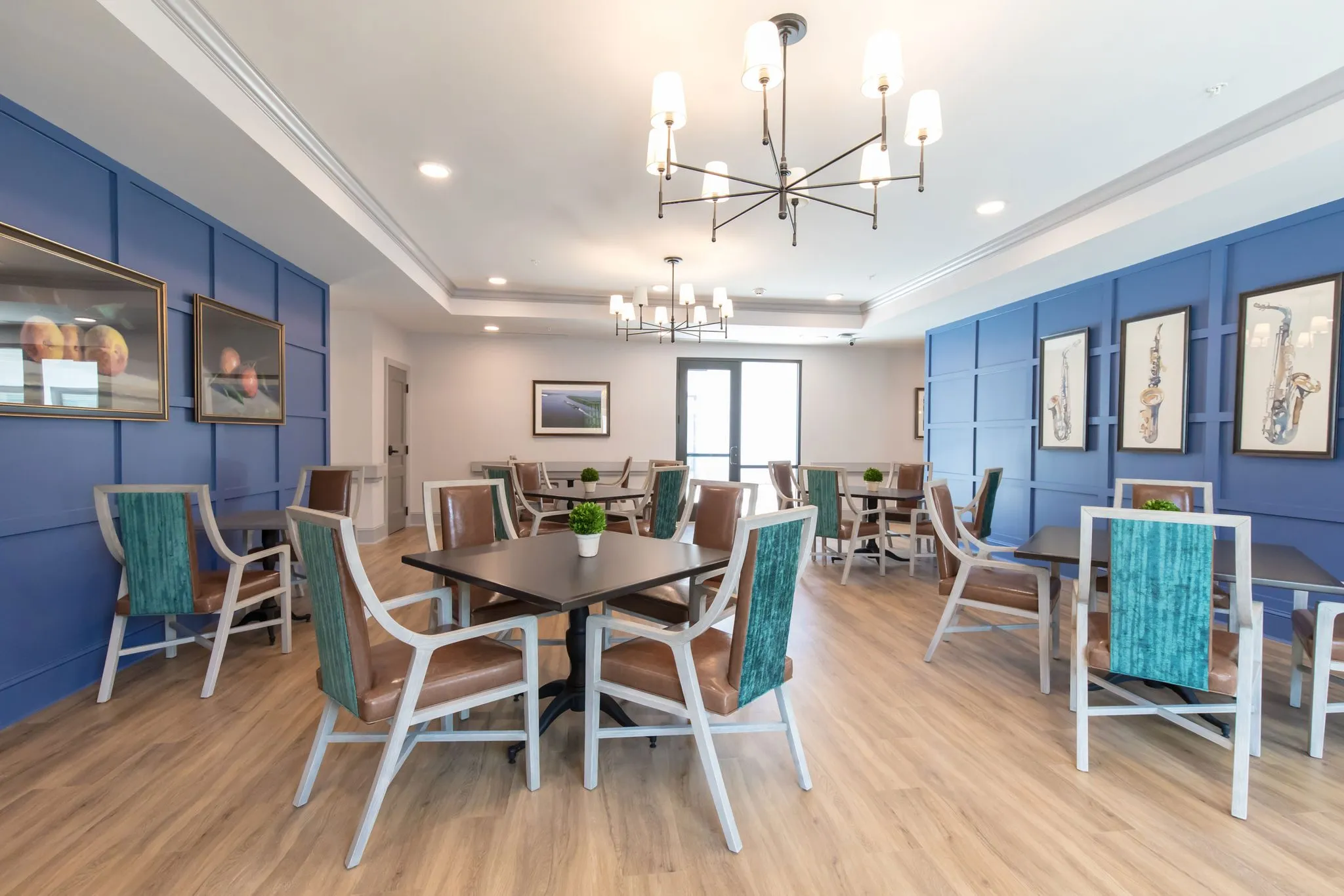 Senior living activity room with framed saxophone artwork on royal blue panelling above white and leather chairs