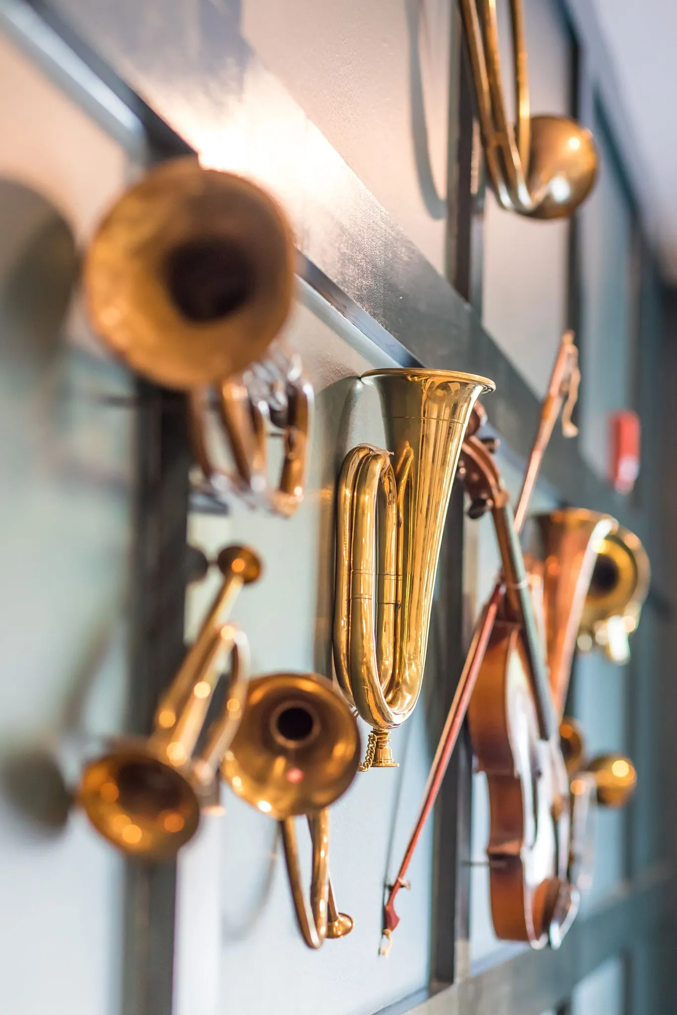 Senior living interior detail: brass horns and a violin mounted close together on the panelled wall