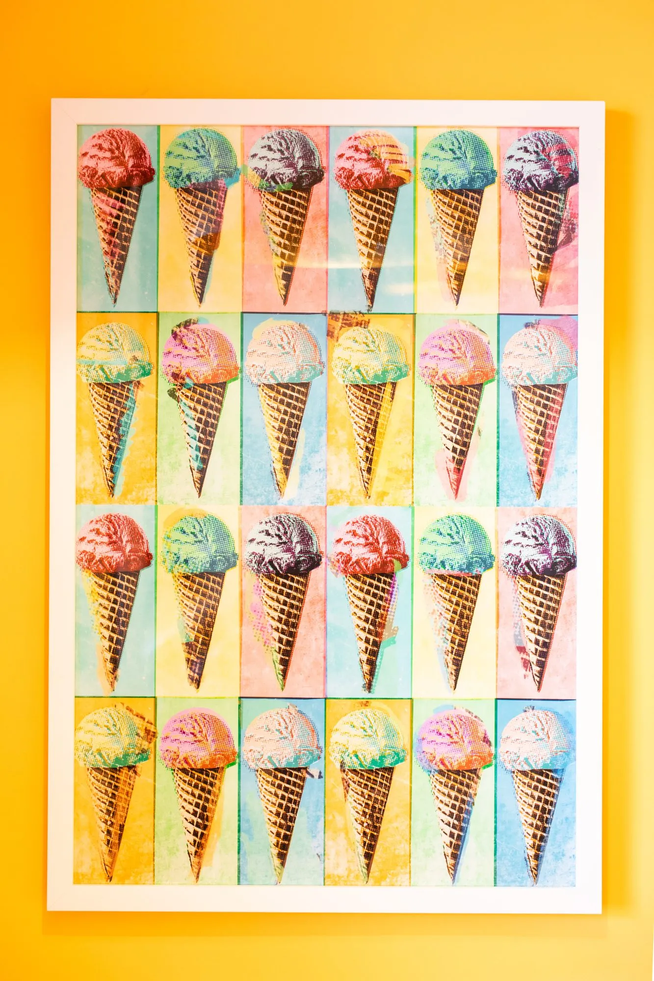 Student housing interior detail: framed grid of pop art ice cream cone prints on a bright yellow wall