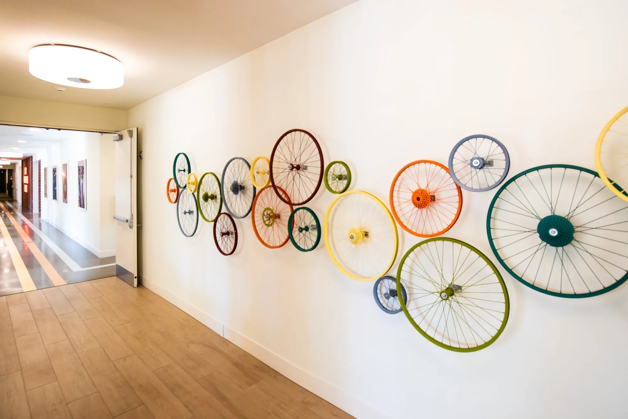 Student housing amenity corridor with a wall of bicycle wheels in assorted colours and sizes