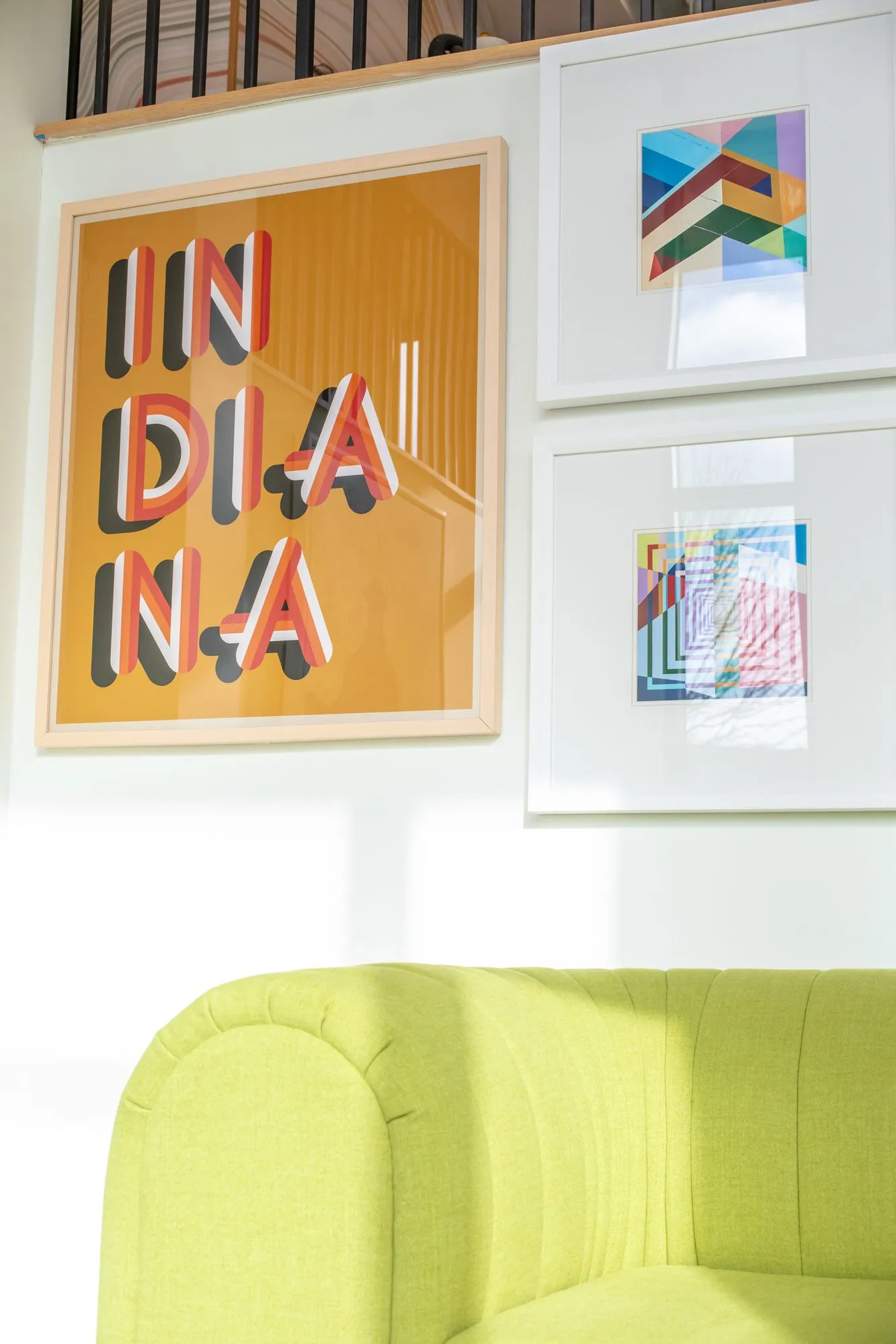 Student housing interior detail: framed INDIANA typographic print and geometric prints above a lime green sofa