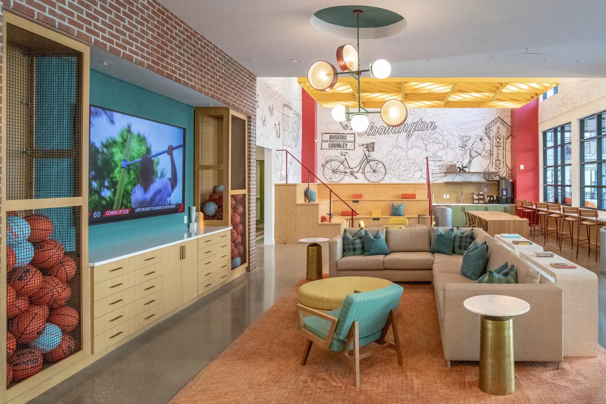Student housing amenity lounge from the basketball cubbies and wall screen across the sectional to the bicycle mural and bar