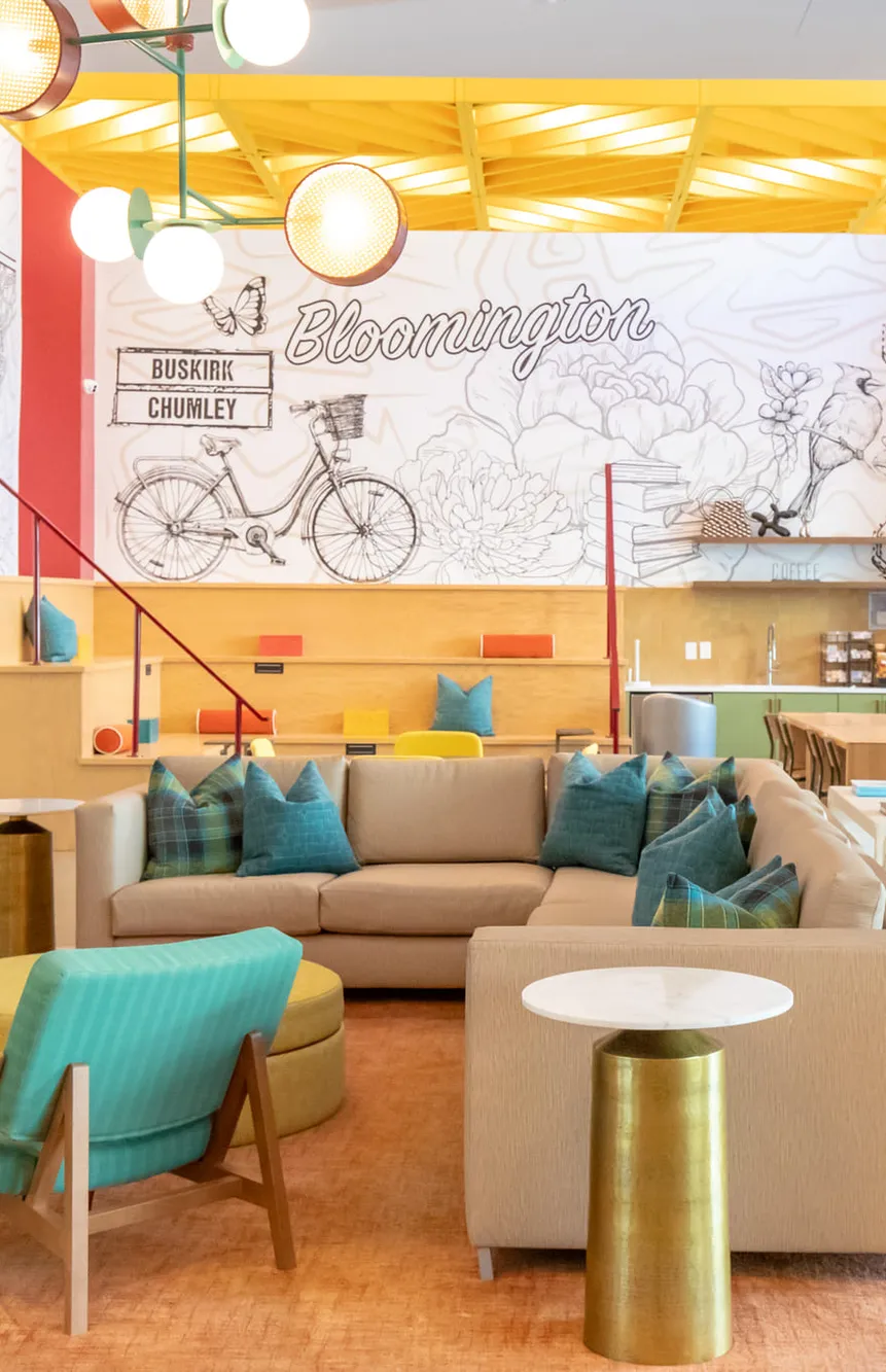 Student housing clubroom below yellow trusses with a line drawn bicycle mural, interior design by Banko Design at Relato Apartments, Bloomington, Indiana