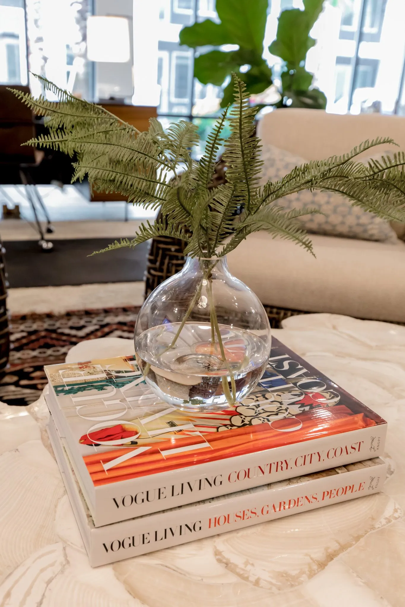 Multifamily interior detail: glass vase with fern fronds on a stack of coffee table books
