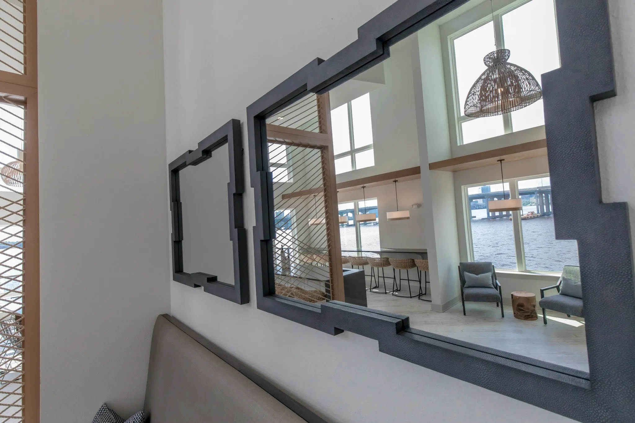 Multifamily interior detail: two black framed mirrors at an angle reflecting the clubroom and river beyond