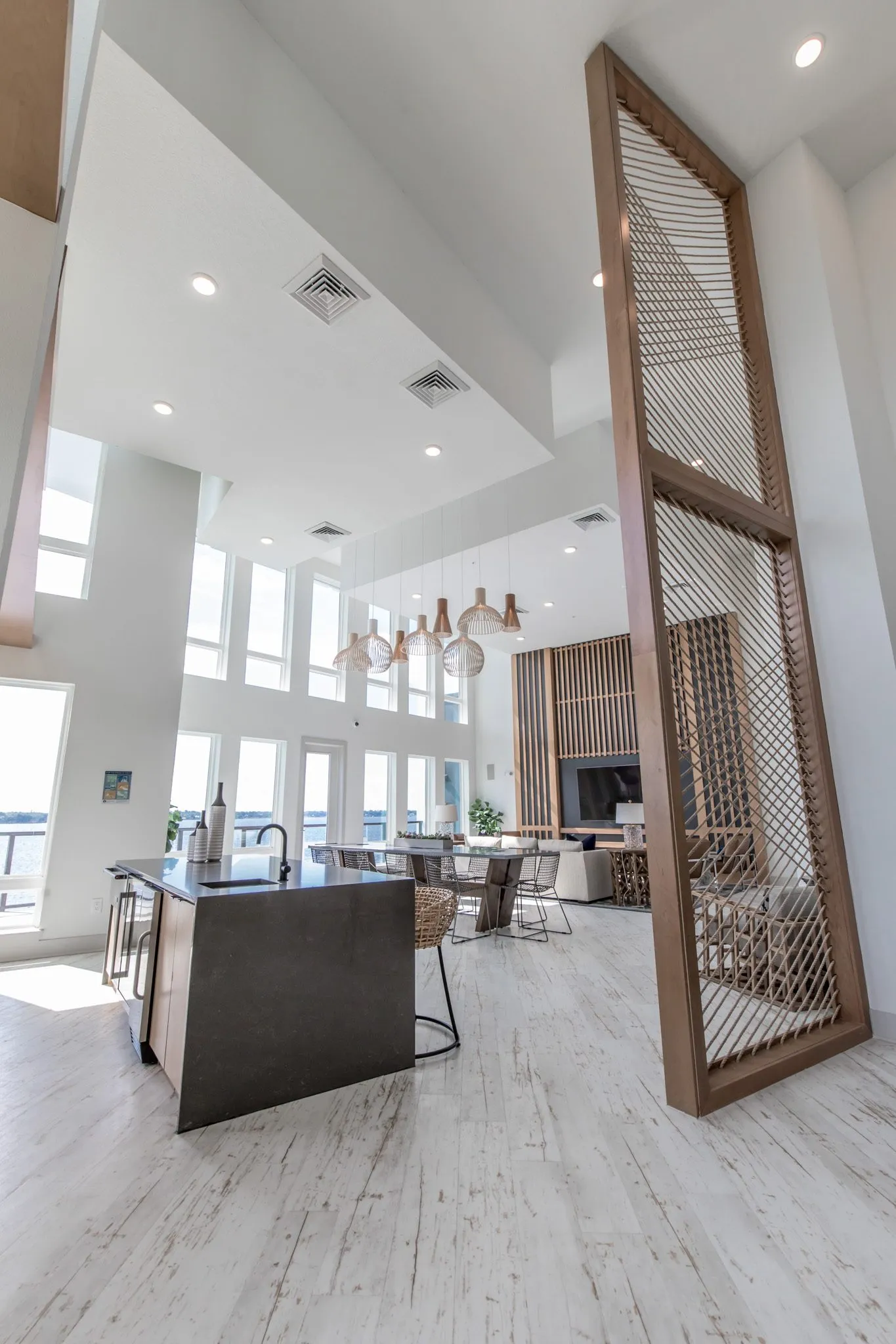 Multifamily amenity double-height clubroom behind a tall rope screen, the island in front