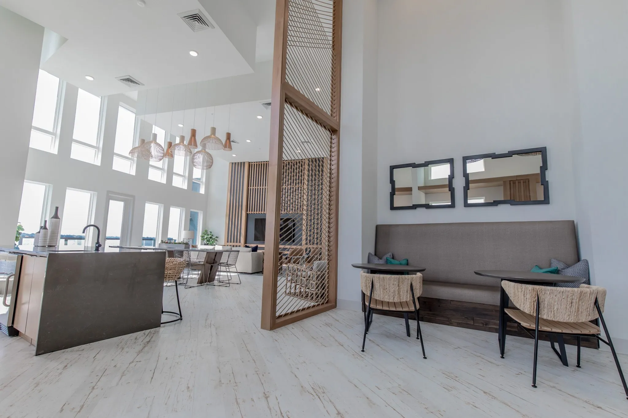 Multifamily amenity clubroom, a low view of the banquette under black framed mirrors and the island beside the rope screen