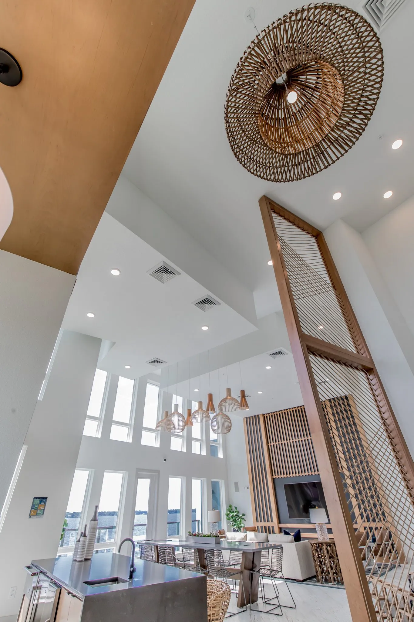 Multifamily amenity clubroom: looking up past a round woven pendant and the rope screen to the clerestory windows