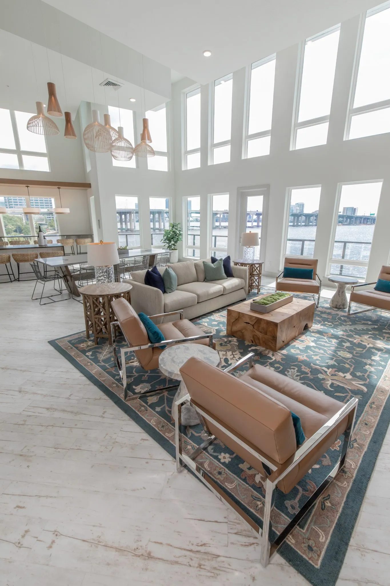 Multifamily amenity clubroom from above, leather sling chairs and a sofa around a timber block table on a blue rug