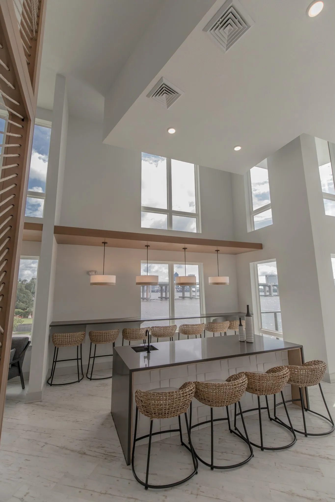 Multifamily amenity clubroom island with woven stools and the window bar below clerestory windows