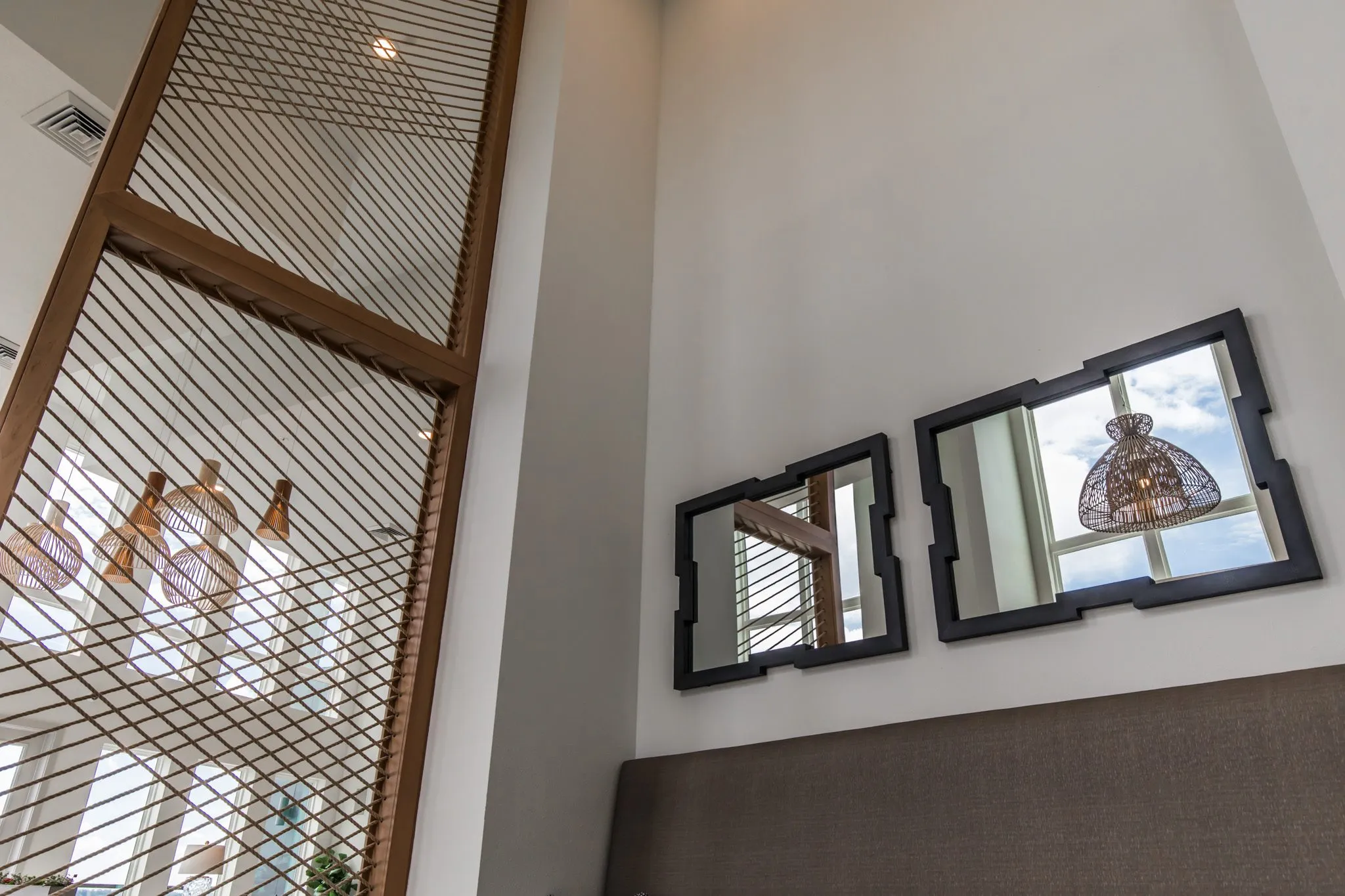 Multifamily interior detail: looking up at two black framed mirrors above the banquette beside the rope screen