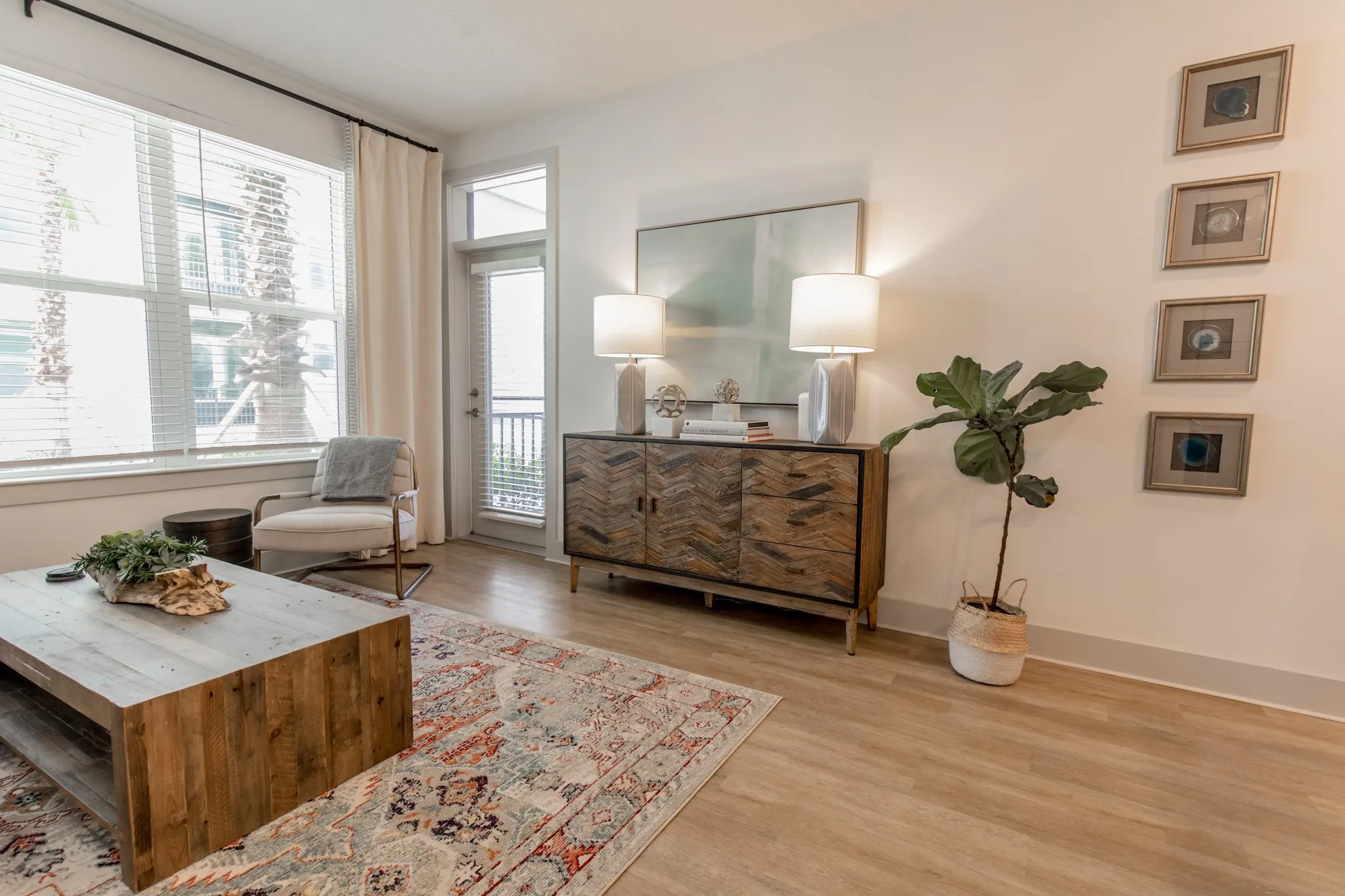 Multifamily model apartment living room with a reclaimed wood coffee table on a red rug, armchair and sideboard