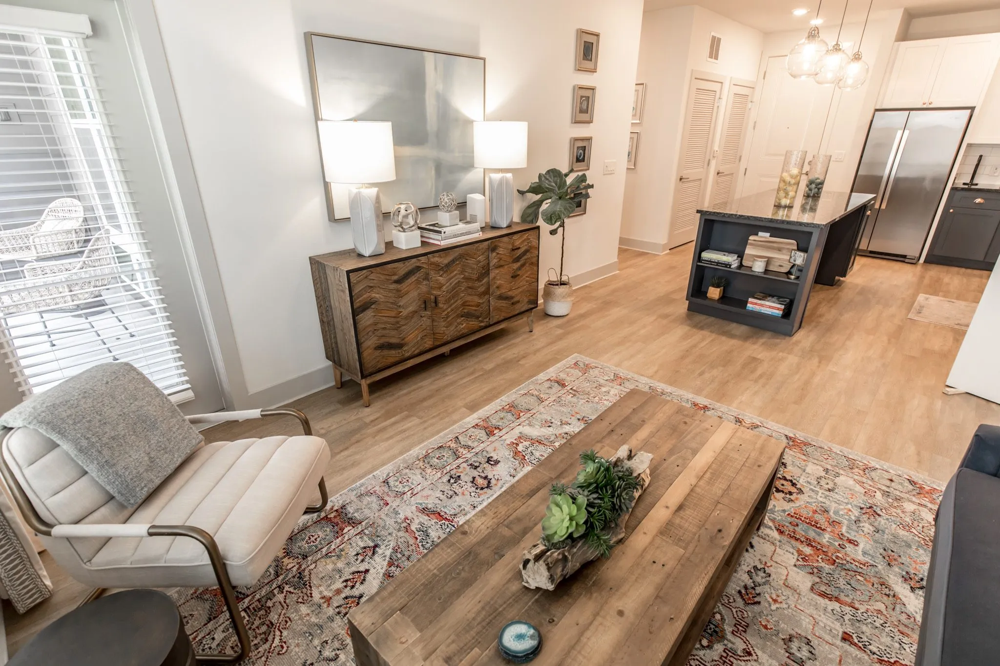 Multifamily model apartment living room from above, toward the kitchen, armchair and sideboard on a red rug