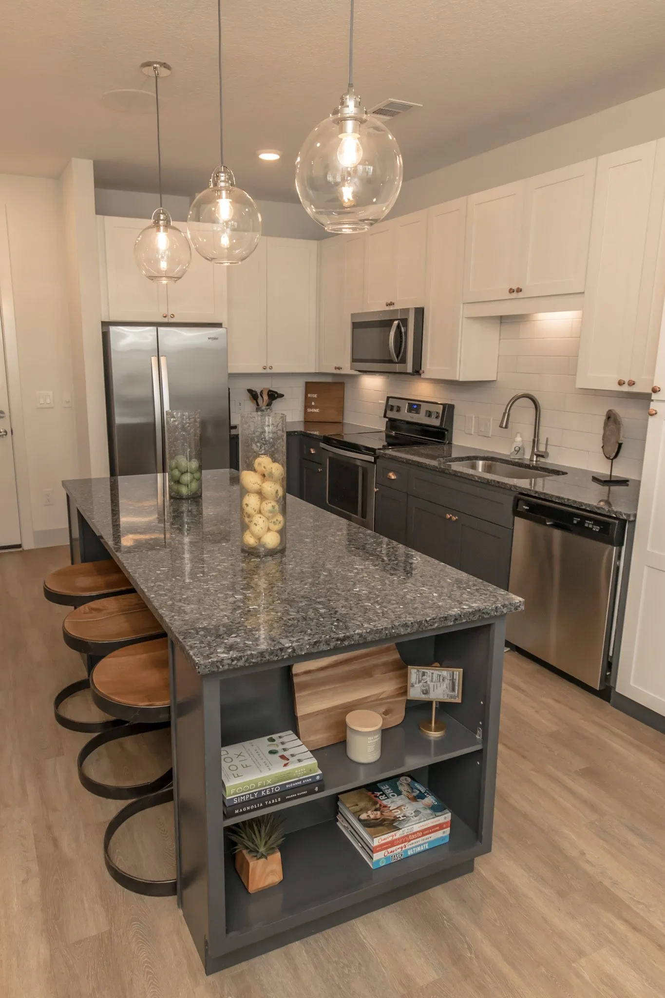 Multifamily kitchen island in granite with jars of lemons and limes, stools and stainless appliances