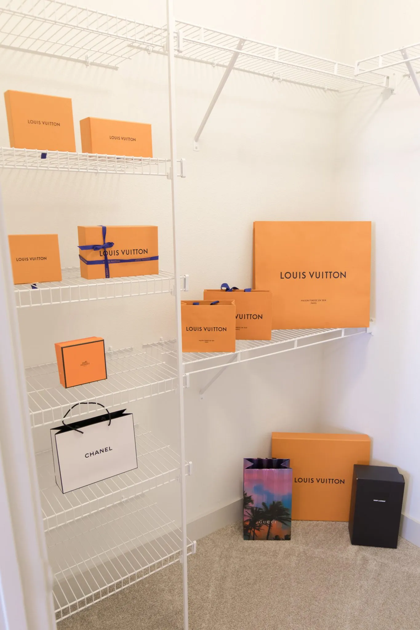 Multifamily apartment walk-in closet with wire shelving holding orange shopping boxes and bags