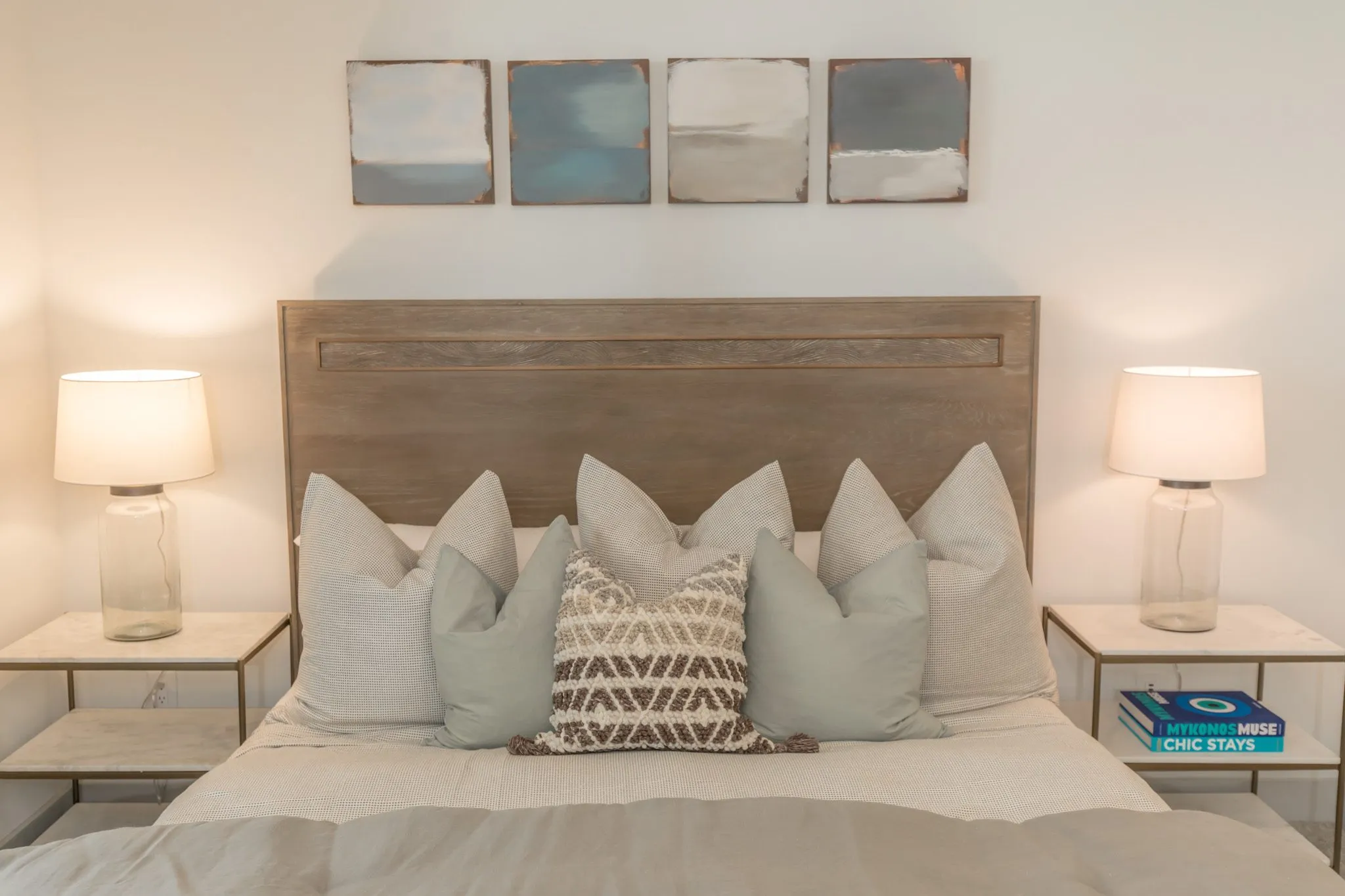 Multifamily apartment bedroom detail: wood headboard and pillows between glass lamps on bedside tables