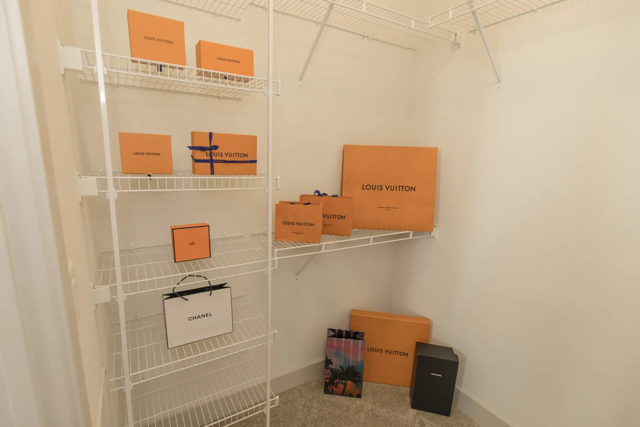 Multifamily apartment walk-in closet in a landscape view, wire shelving with orange shopping boxes and bags