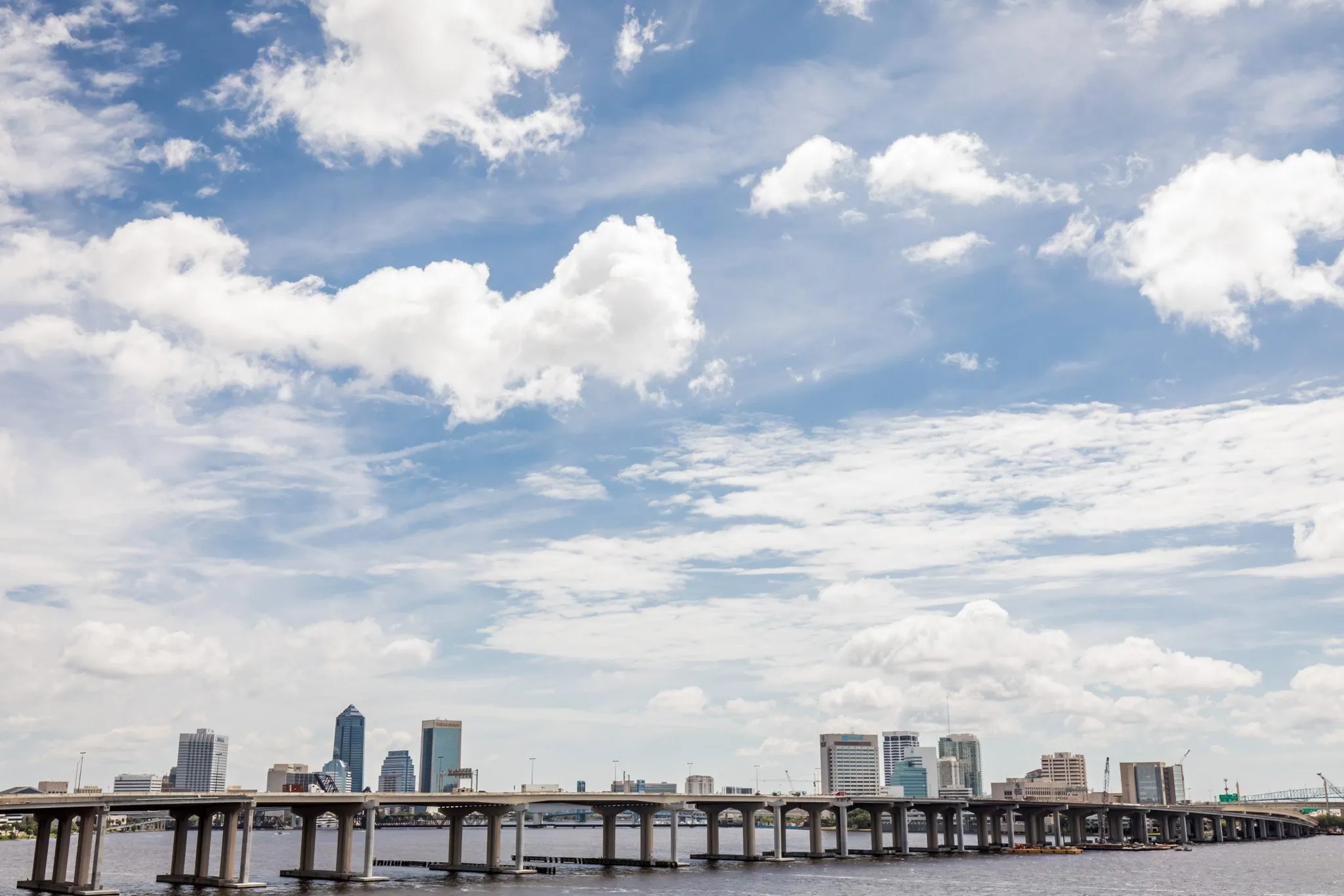 Multifamily community exterior: river view with a long bridge and the downtown skyline under a cloudy sky