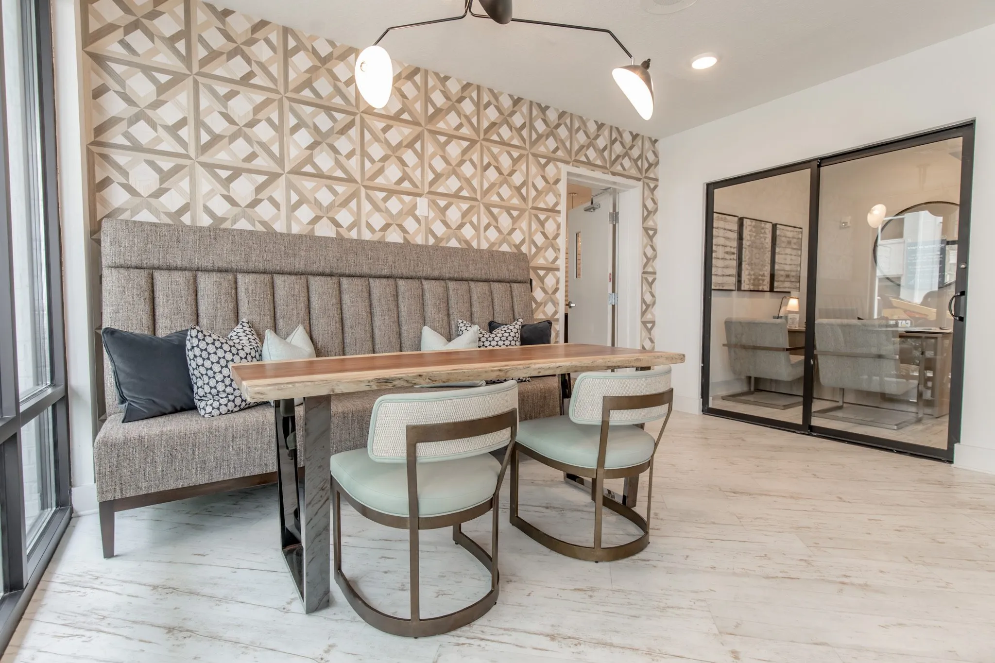 Multifamily interior detail: grey channel tufted banquette at a live edge table with sage chairs before parquet wallcovering