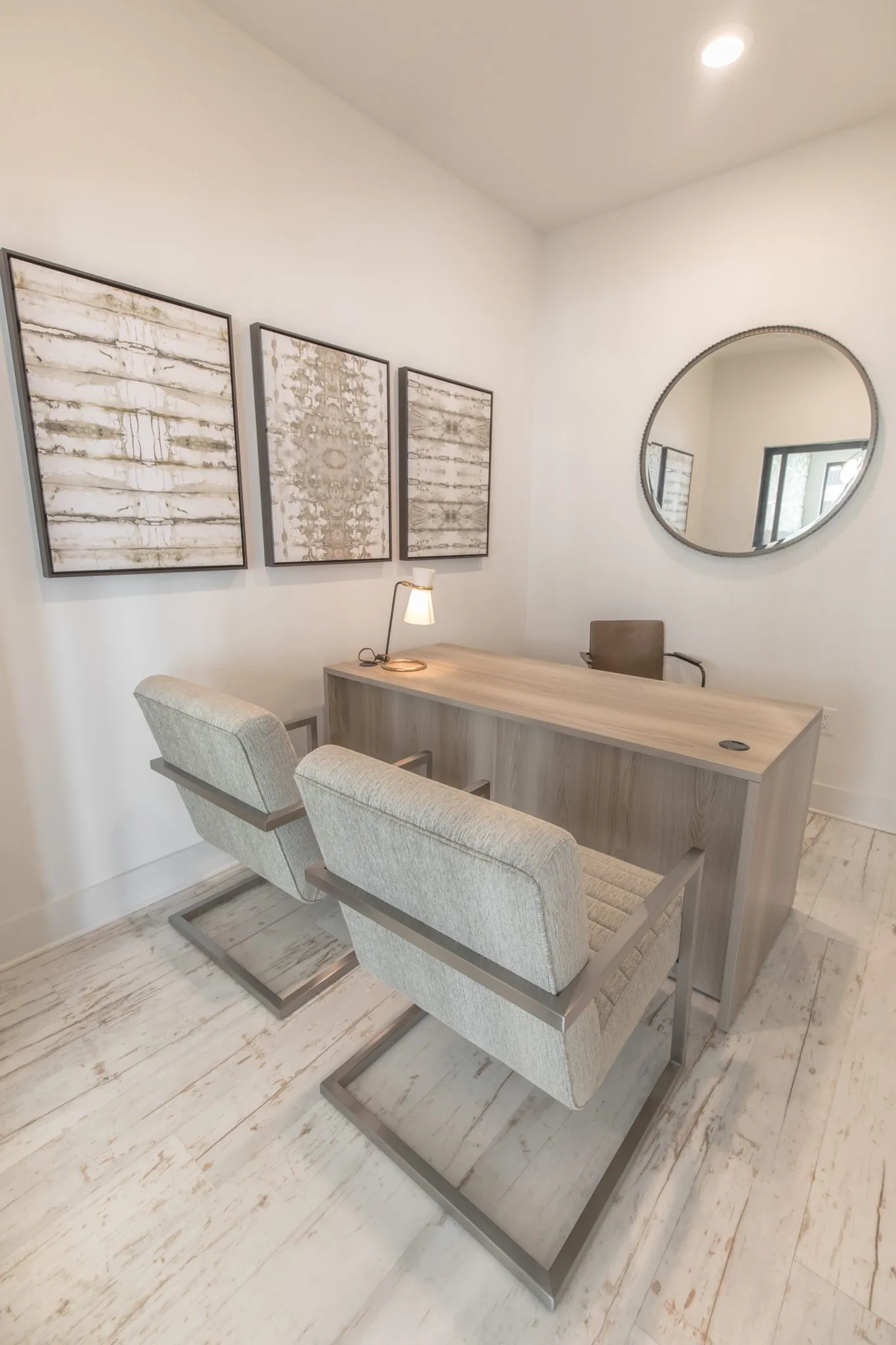 Multifamily amenity office with two cantilever chairs facing the desk below three framed prints