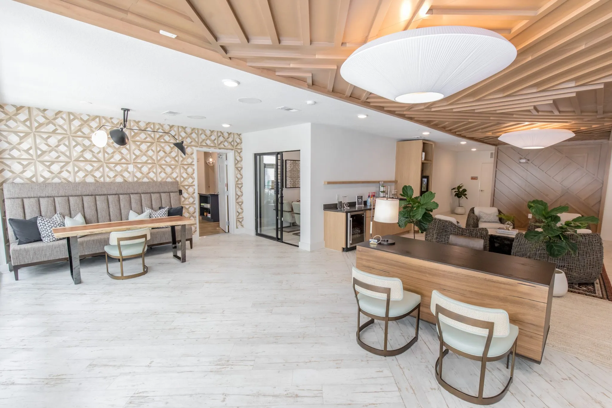 Multifamily amenity leasing area with the banquette and live edge table at left, the desk, kitchenette and lounge at right