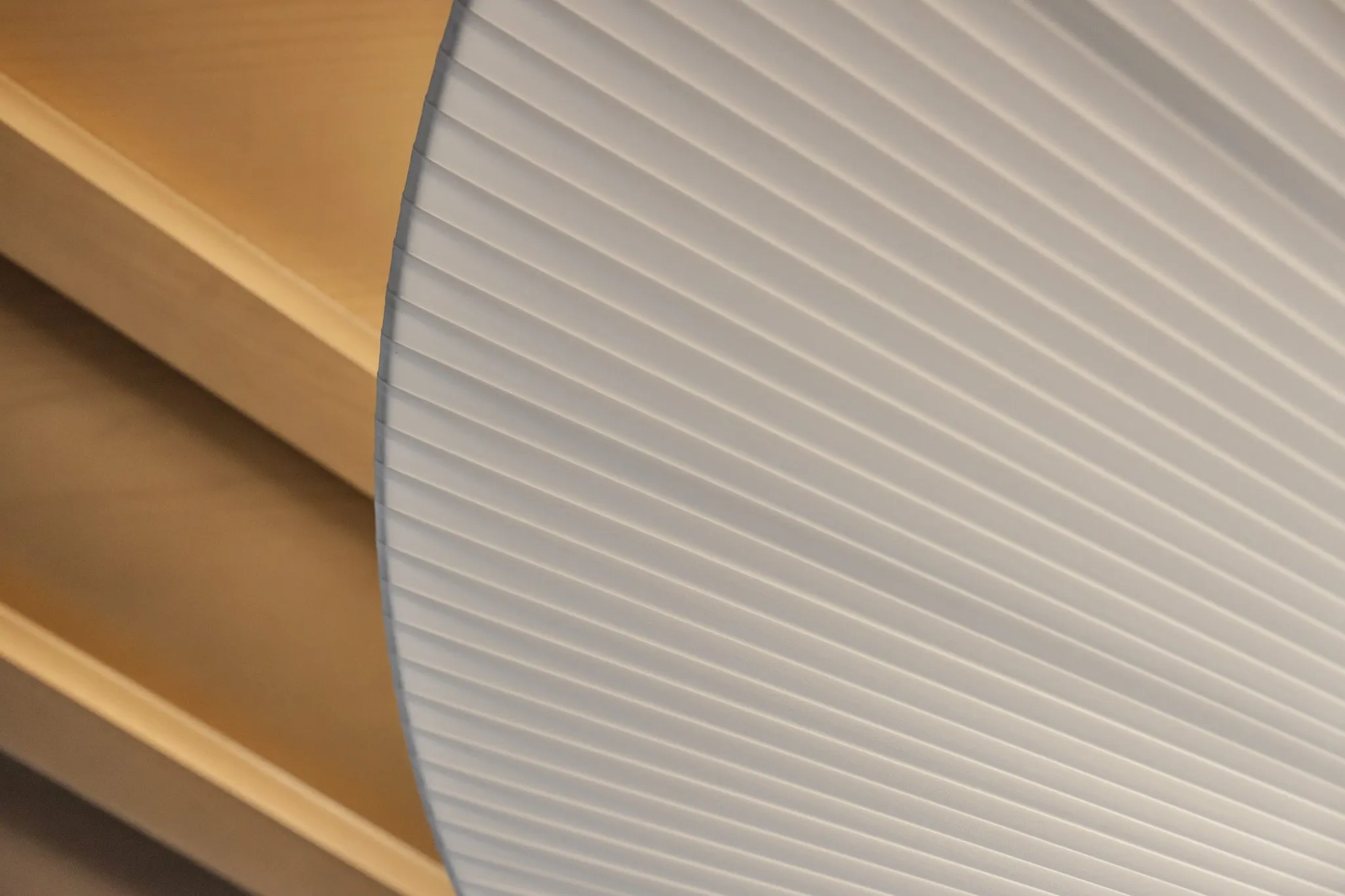 Multifamily interior detail: pleated fabric pendant edge against wood ceiling slats