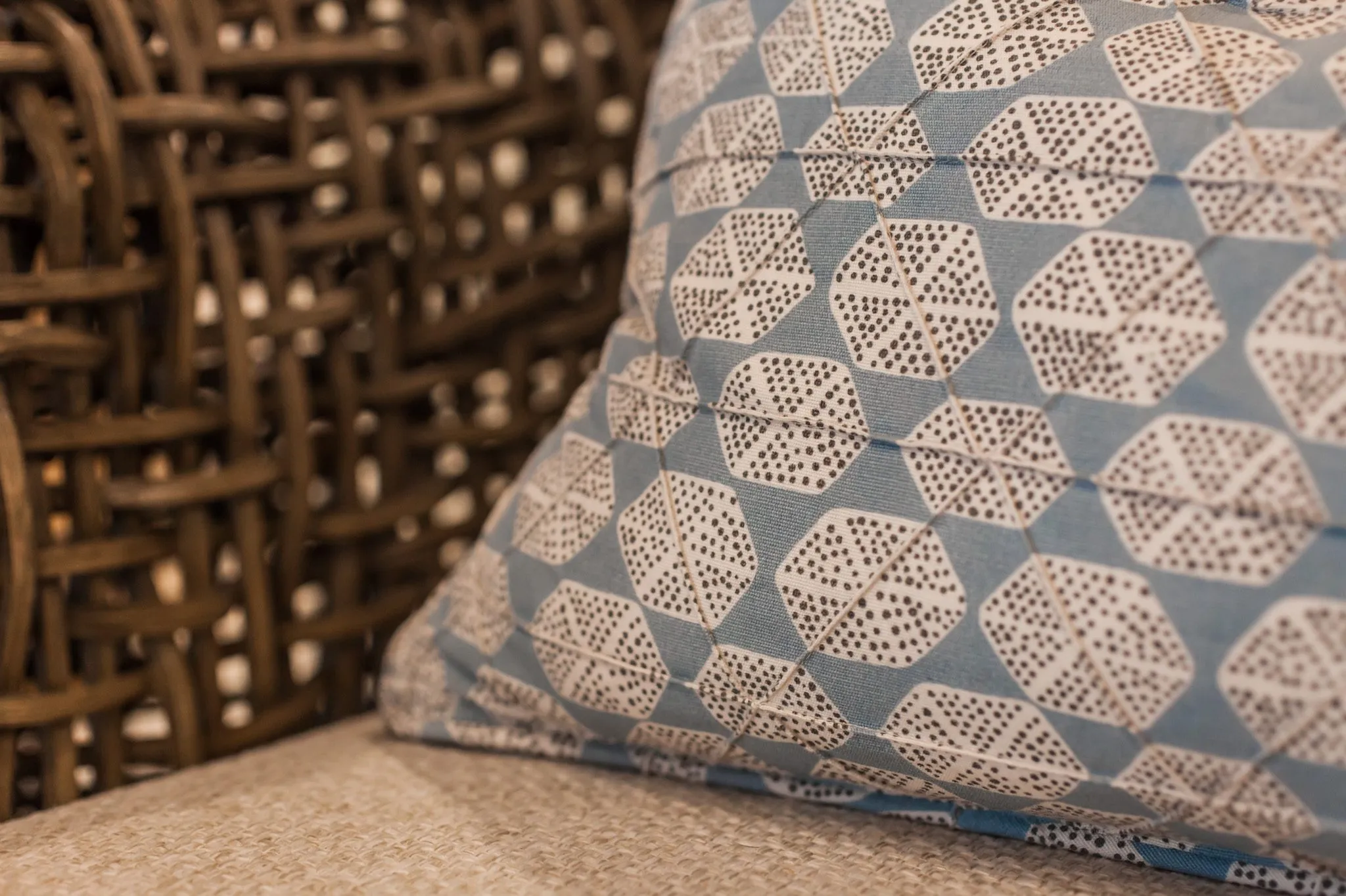 Multifamily interior detail: blue and white geometric print pillow against a woven chair