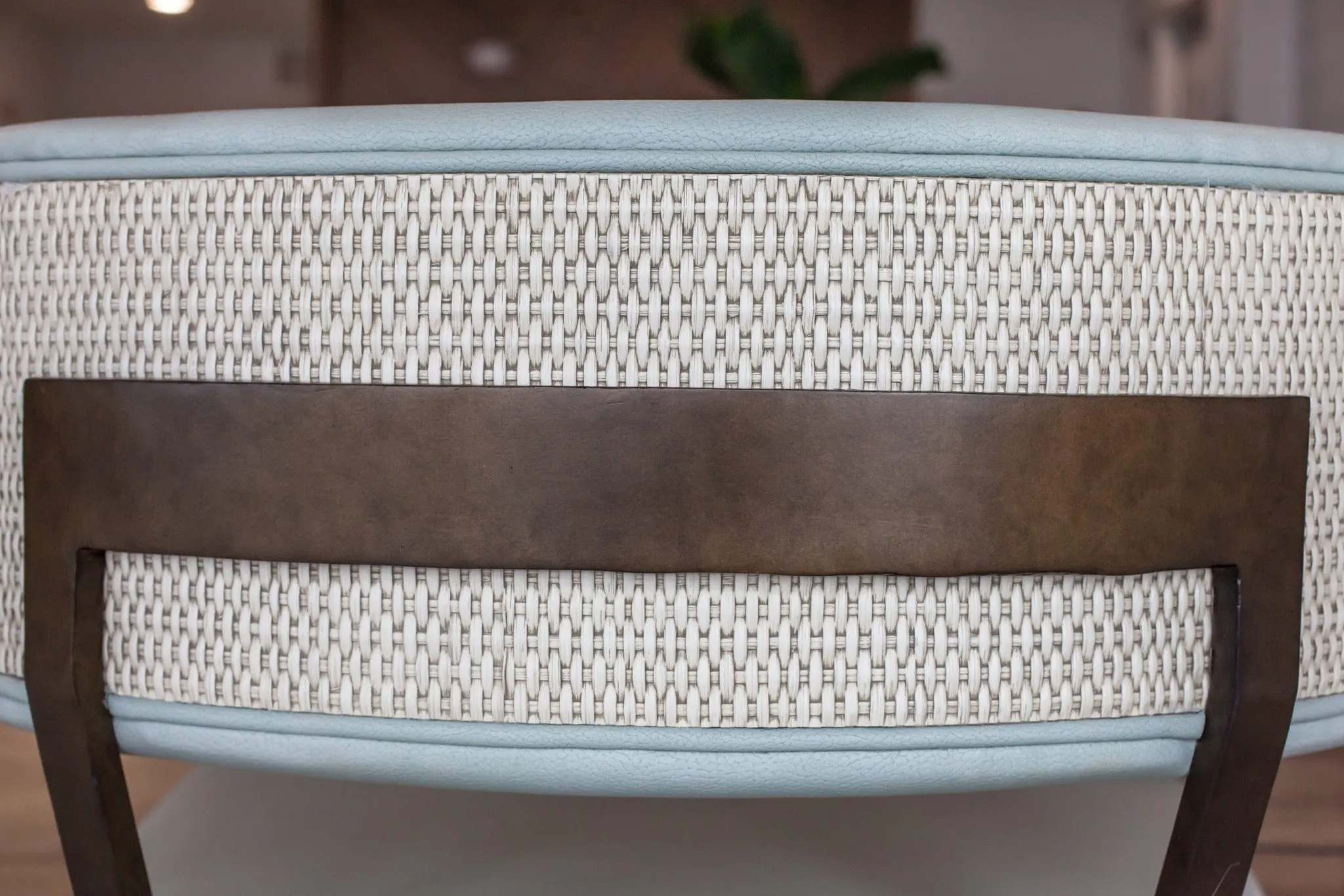 Multifamily interior detail: woven fabric chair back with pale blue piping and a bronze frame