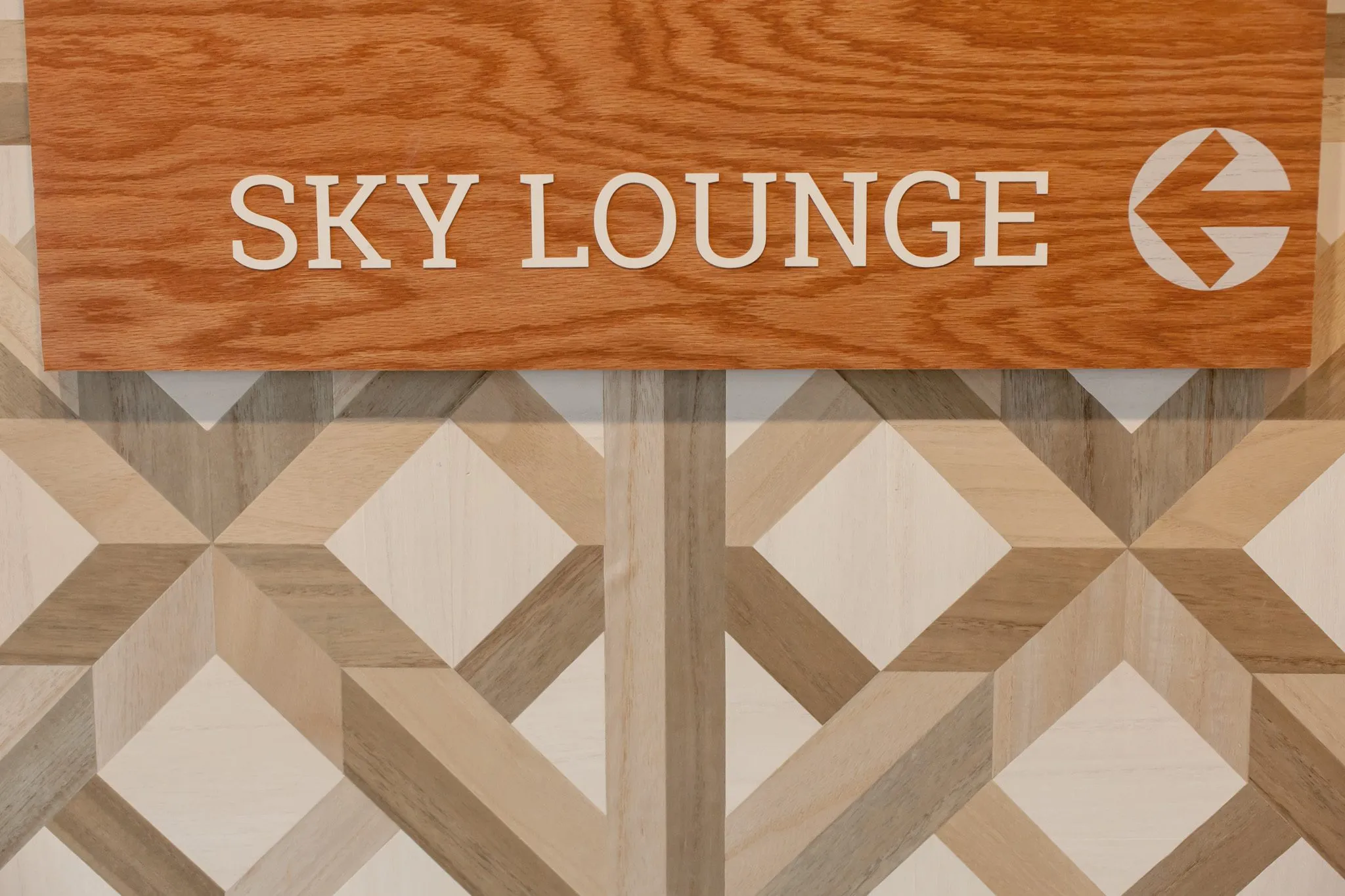 Multifamily interior detail: wood sign reading Sky Lounge with an arrow on parquet pattern wallcovering