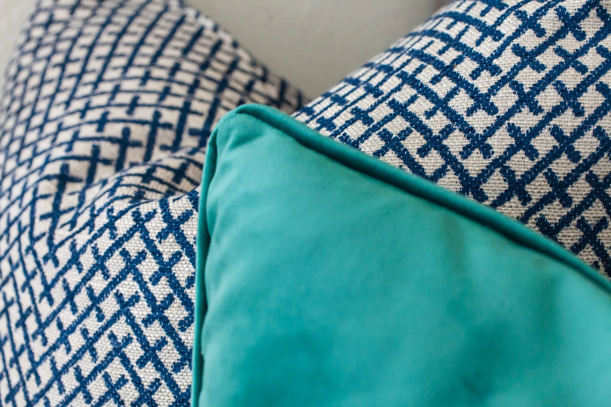Multifamily interior detail: teal velvet pillow against blue and cream lattice pattern pillows