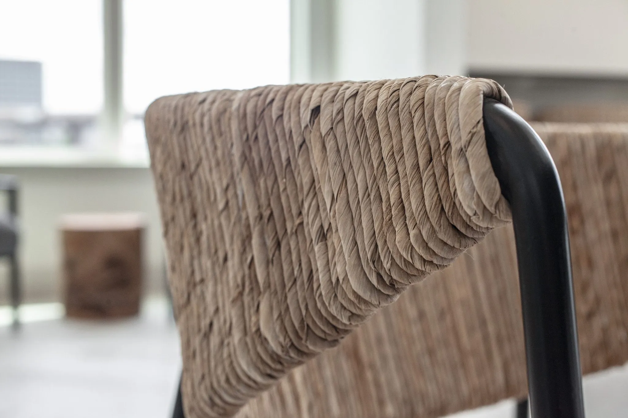Multifamily interior detail: woven seagrass chair back on a black metal frame
