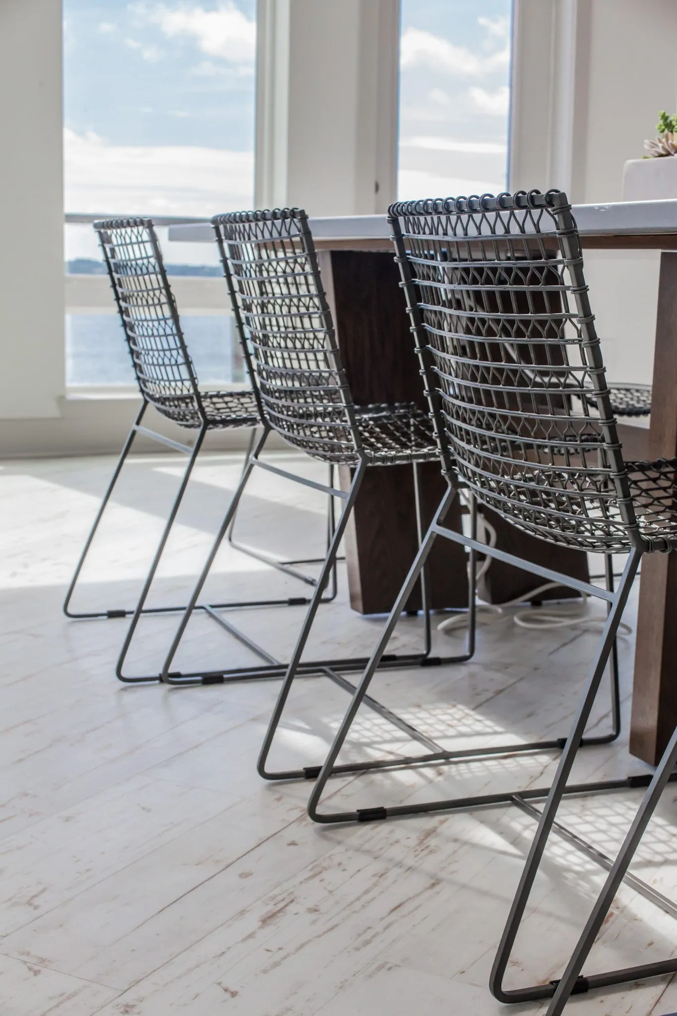Multifamily interior detail: black wire chairs at the long table, river view windows behind